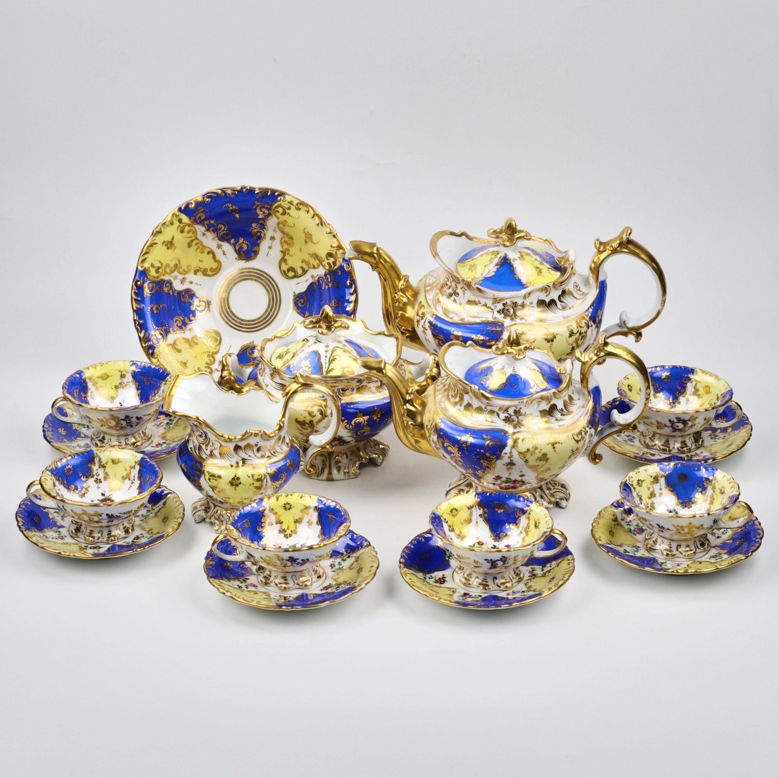 Tea set of the second baroque.: Tea set, neo-baroque style. Includes: 2 teapots, creamer, sugar bowl, rusk bowl and 6 tea pairs. Made in royal shades of yellow and blue with a painted floral pattern with whimsical lace forms. Large 