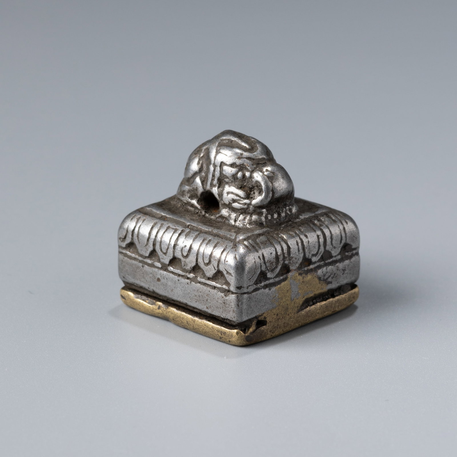 Tibetan Bronze and Iron Seal with Conch Motif: A Tibetan seal crafted from bronze and iron, featuring a conch shell motif. Measures 2.6 x 2.6 cm and weighs 56 grams.