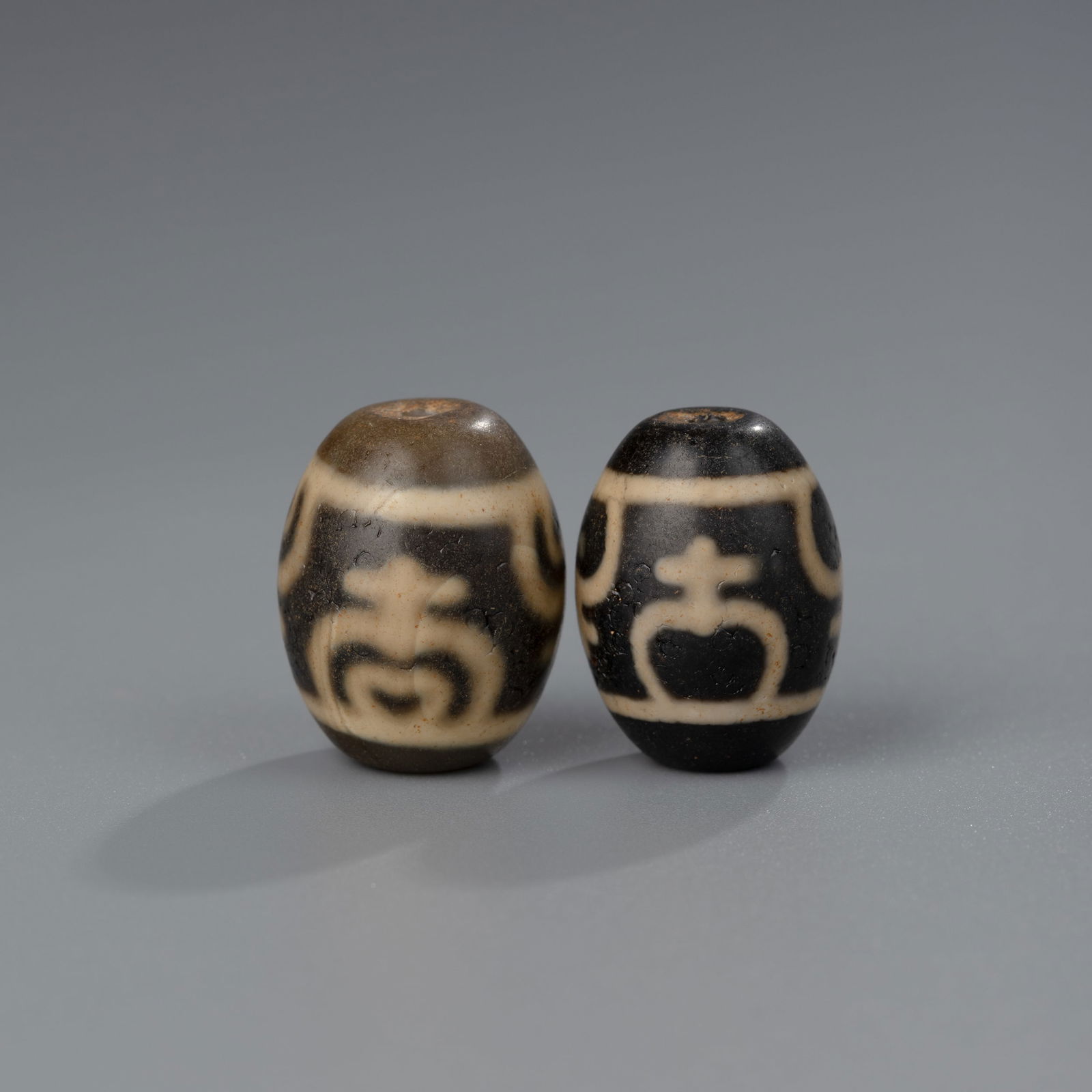 Tibetan Nectar Bottle and Lotus Dzi Bead Amulets (2 pcs): A pair of Tibetan Dzi beads, one in the shape of a nectar bottle and the other featuring a lotus motif. These symbolic amulet beads measure approximately 2 x 1.5 cm each and have a combined weight of