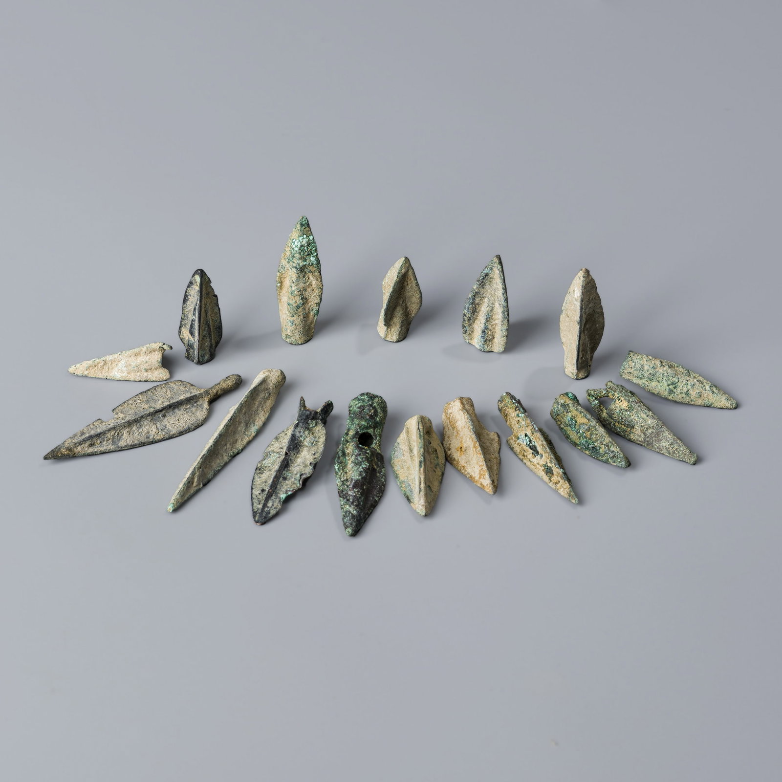 Group of 16 Ancient Bronze Arrowheads from Near Eastern Regions – Roman & Greek Periods: A collection of 16 ancient bronze arrowheads from Near Eastern regions, dating to the Roman and Greek cultural periods. Each piece displays authentic patina and craftsmanship typical of these historic