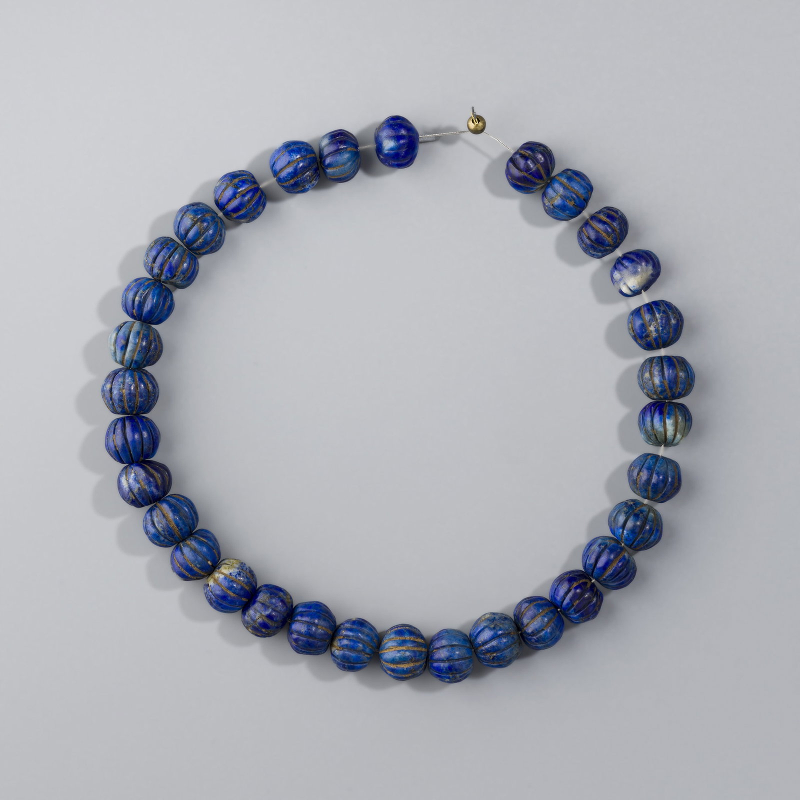 Near Eastern Bactrian Natural Blue Lapis Lazuli Carved Melon-Shaped Beads Lot: A lot of 32 natural blue lapis lazuli beads from the Near Eastern Bactrian region, intricately carved in a melon shape. Weighing approximately 55 grams.