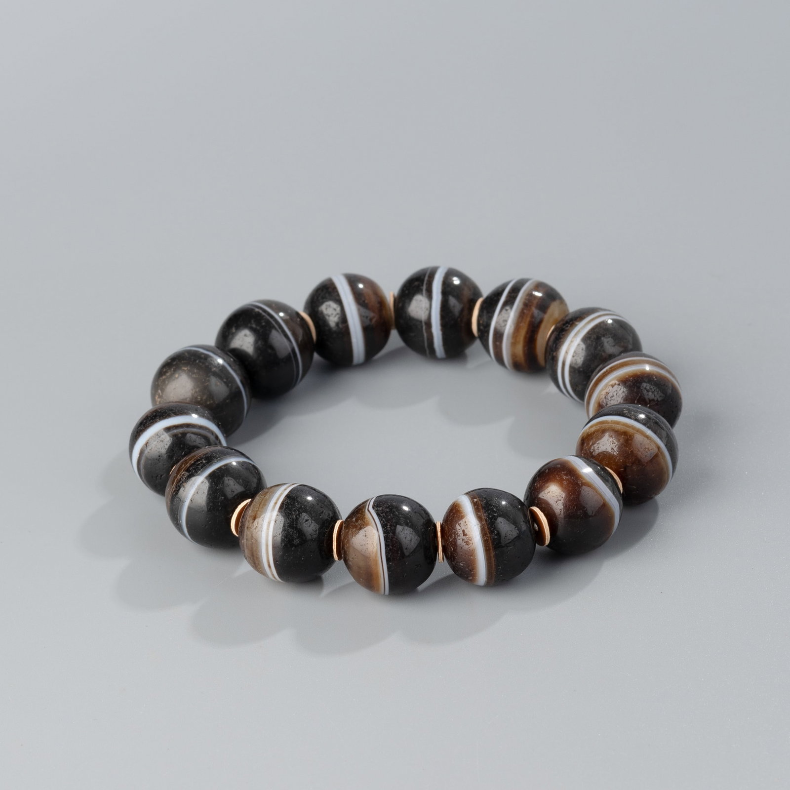 Antique Himalayan Tibetan Banded Babagoria Agate Beaded Bracelet: A stretchable cord bracelet featuring 14 natural banded Babagoria agate beads from the Himalayan Tibetan region.Details:Beads: 14 piecesWeight: 70 grams