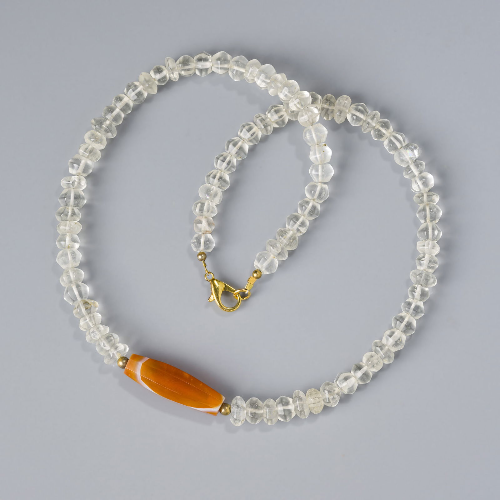 Antique Himalayan Crystal Quartz Bead Necklace with Faceted Carnelian Center: A delicate Himalayan antique necklace composed of crystal quartz beads, highlighted by a central faceted carnelian bead.Length: 20 inWeight: 50 g