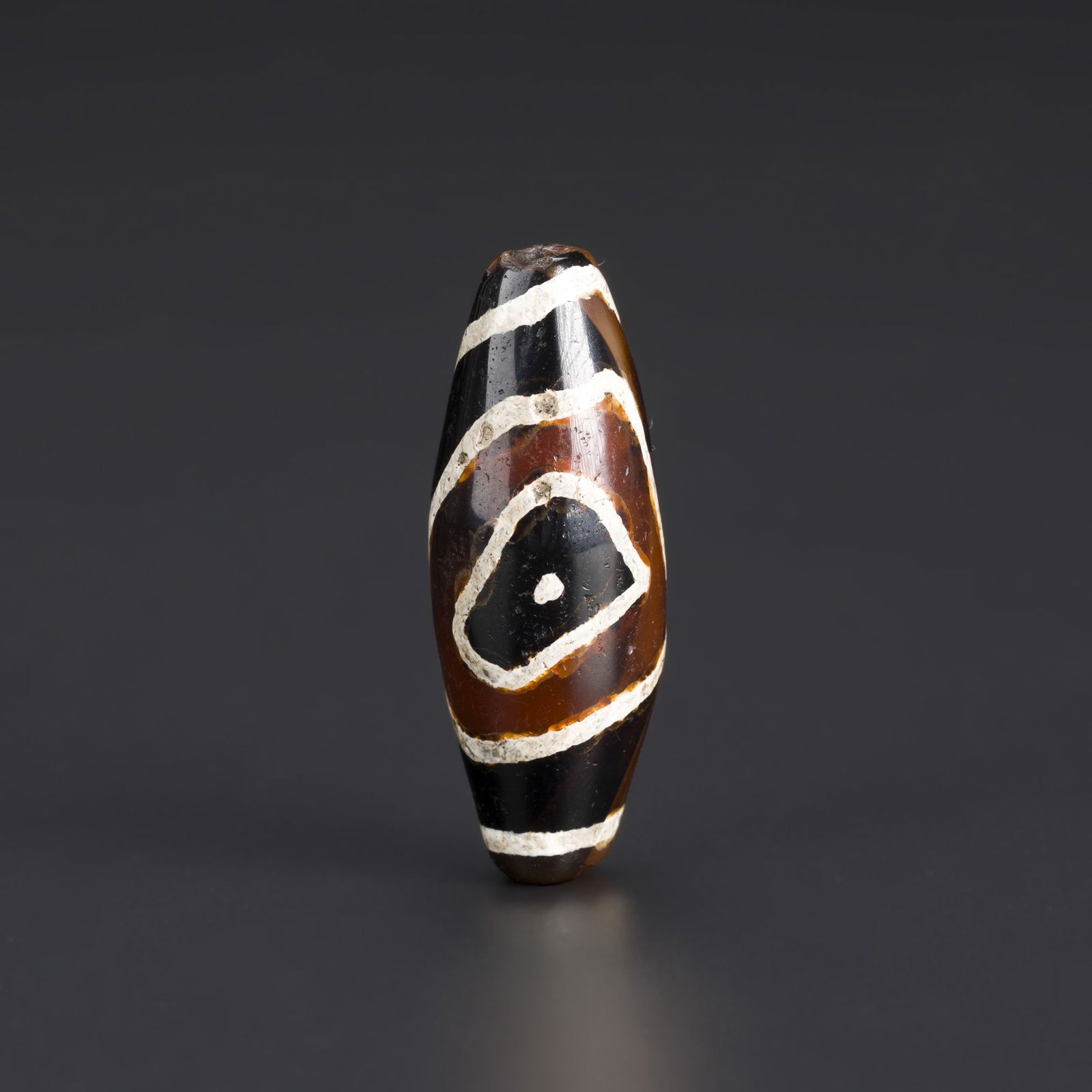 Indo-Tibetan Eye Dzi Bead with Rare Pattern Design: An Indo-Tibetan eye Dzi bead featuring a rare and distinctive pattern. Crafted from agate with a naturally worn surface, this bead is prized for its unique design, cultural significance, and appeal to