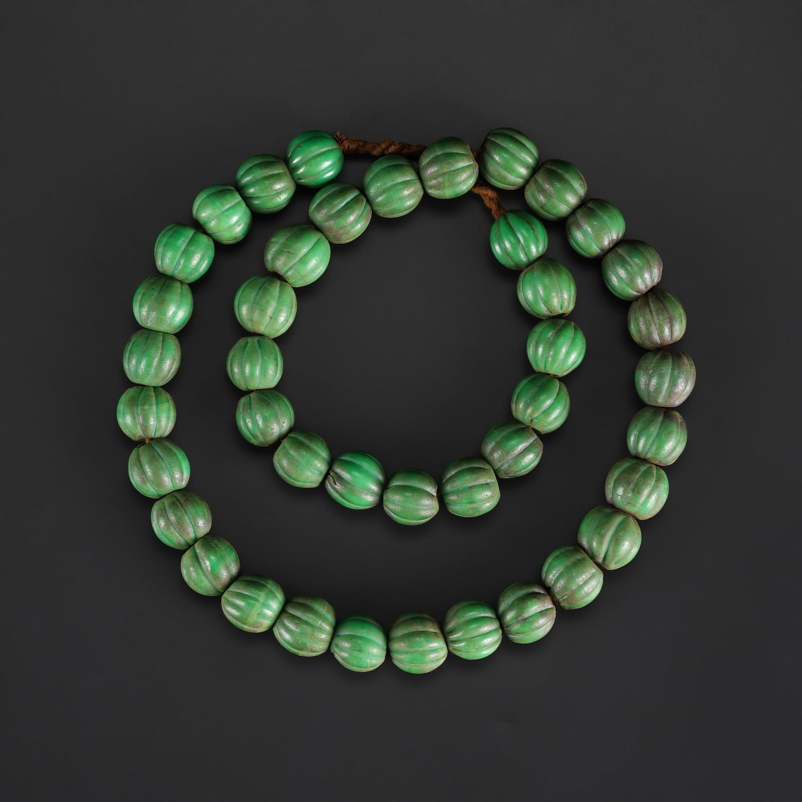 An Old Glass Melon-Shaped Bead Necklace: A vintage necklace featuring melon-shaped glass beads, exhibiting subtle color variations and surface wear consistent with age. Length: 26.5in Total Weight: 233gram