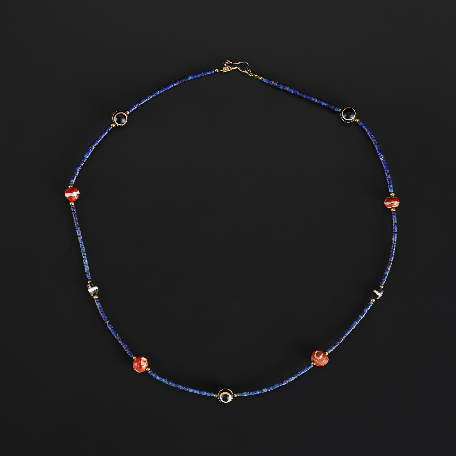 An Ancient Etched Carnelian Ghost-Eye Bead Necklace with Lapis Lazuli Spacers: A necklace featuring ancient etched carnelian ghost-eye beads, interspersed with small lapis lazuli spacer beads, exhibiting rich color and natural patina consistent with age. Length: 20in Total Weigh