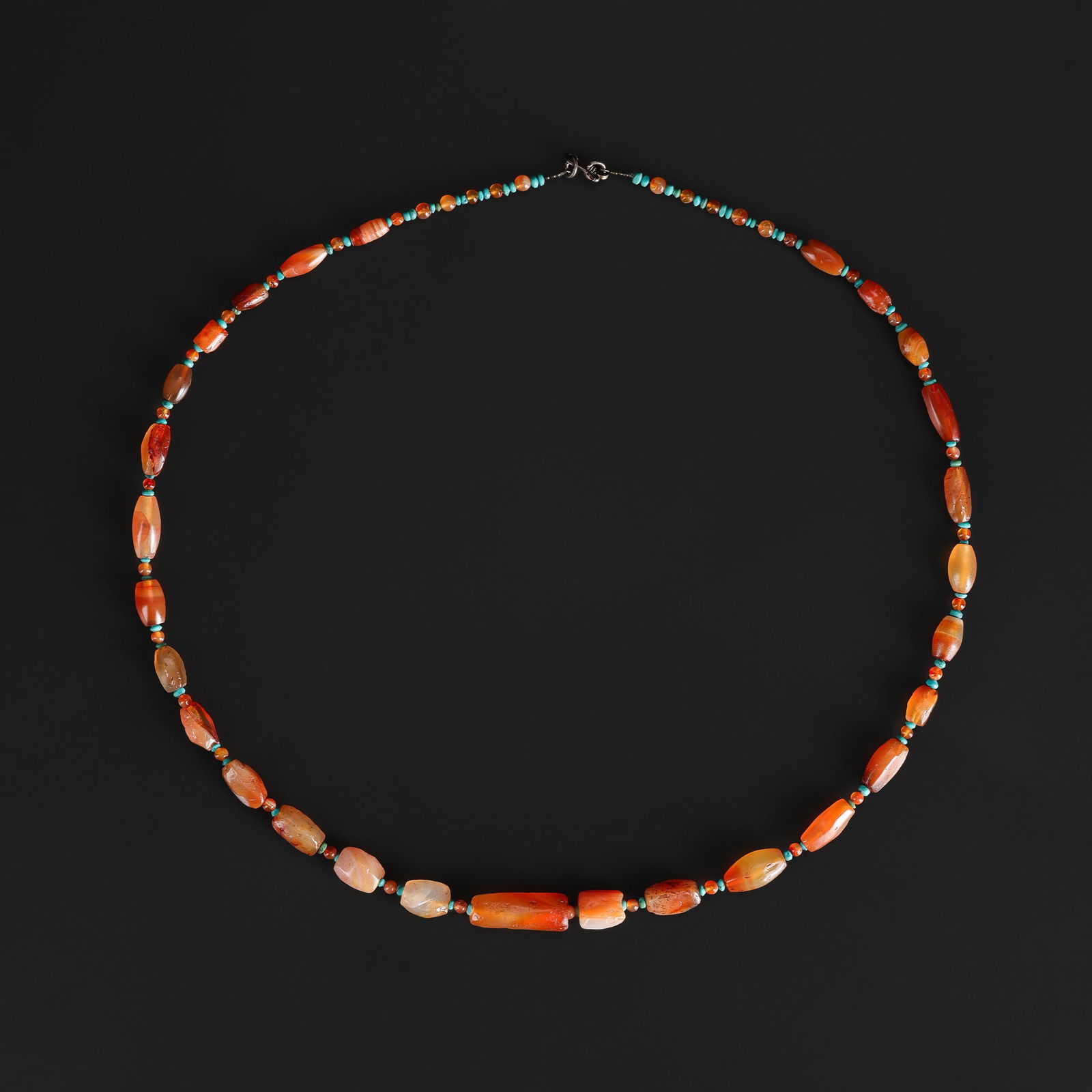 An Ancient Bactrian Carnelian Bead Necklace with Turquoise Spacers: An ancient necklace composed of Bactrian carnelian beads, interspersed with small turquoise spacer beads, exhibiting rich color and natural patina consistent with age. Length: 21in Total Weight: 22gra