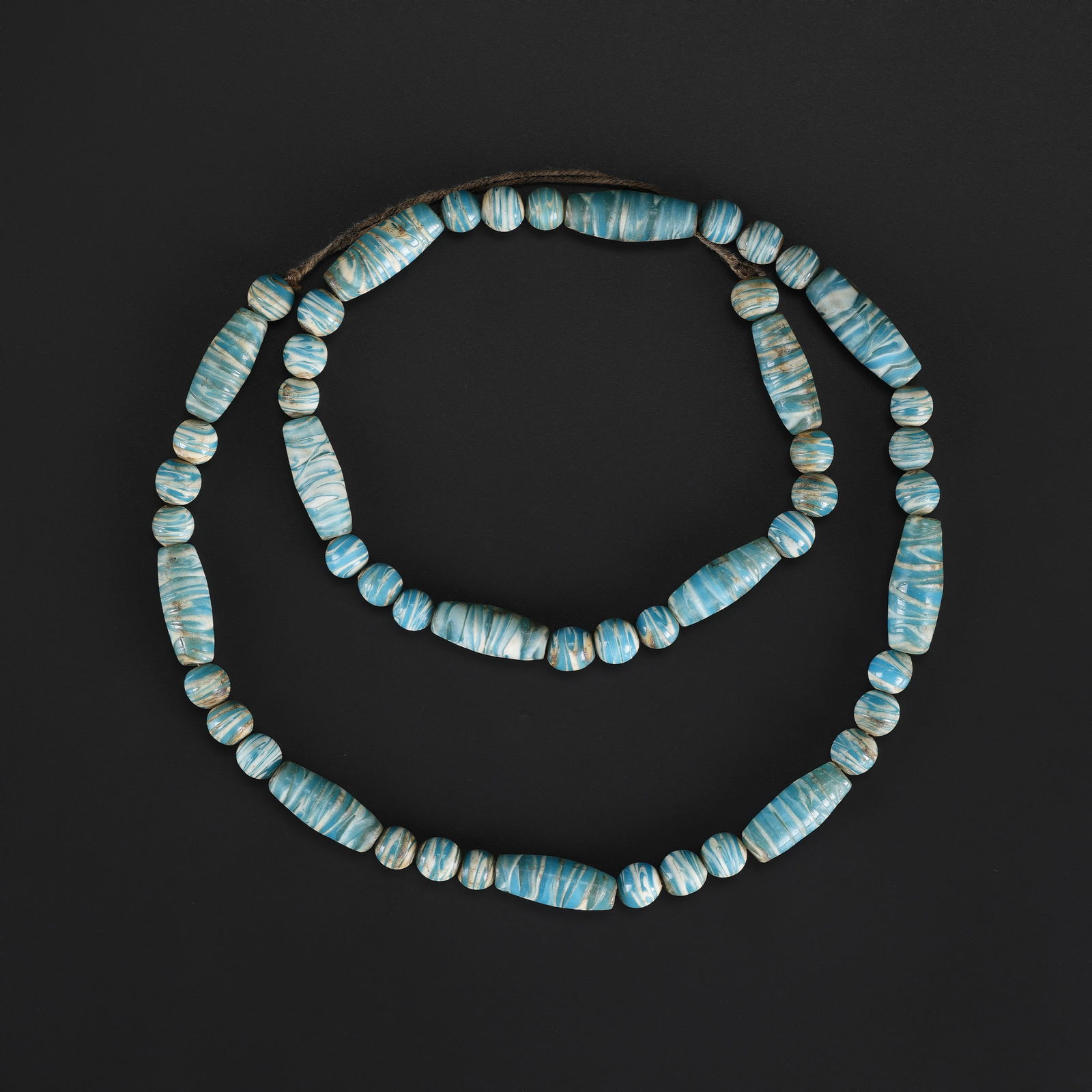 An Antique Blue Barrel-Shaped Glass Bead Necklace with White Banded Lines: An antique necklace composed of barrel-shaped blue glass beads featuring white banded lines, showing natural wear and age-appropriate patina. Length: 28in Total Weight: 101gram
