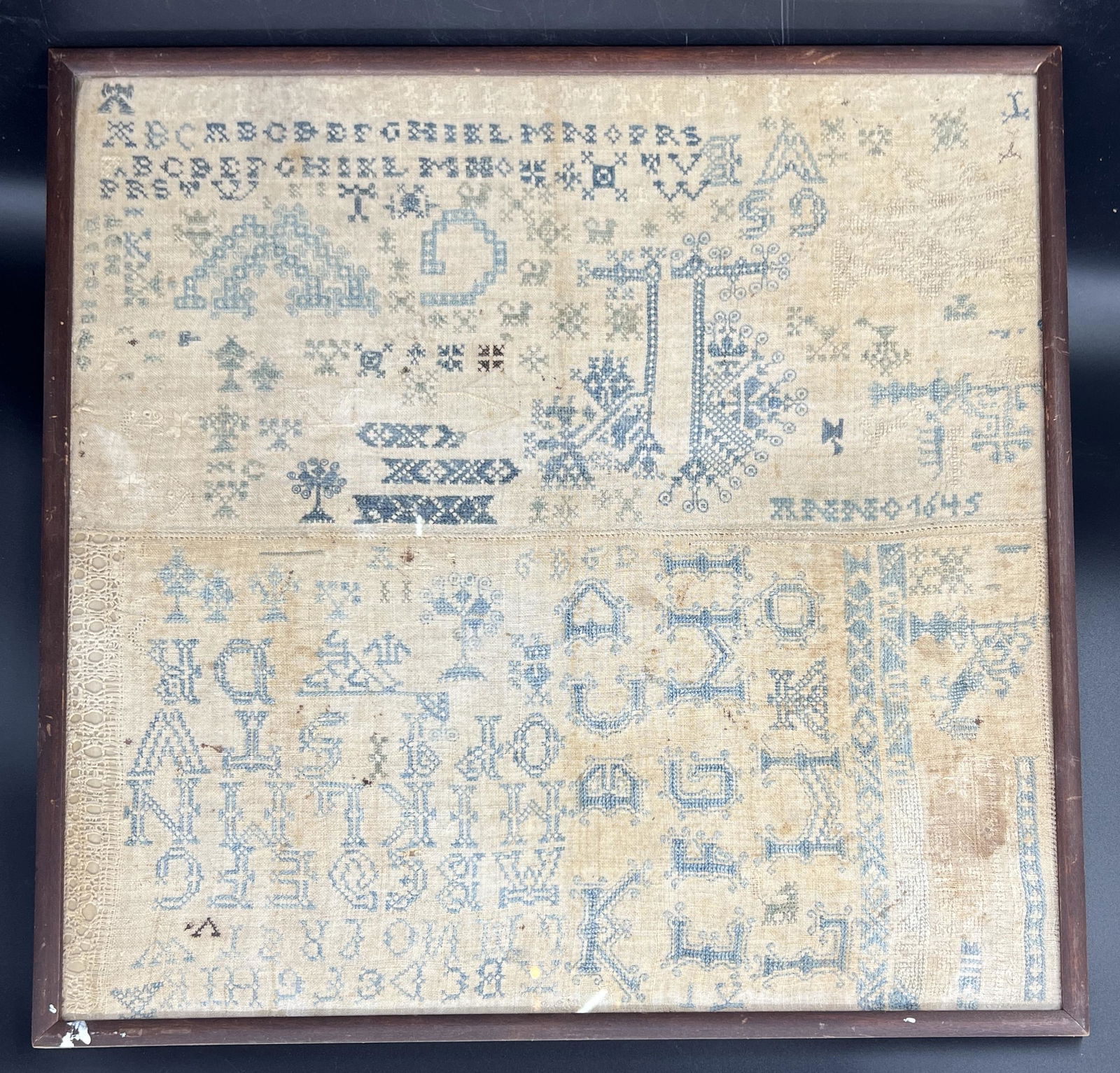 Antique Primitive "Anno 1645" Framed Sampler: Antique primitive sampler. Numbers, alphabet, symbols, and decorative designs. Signed "Anno 1645." 17th century. Folk art. Size: 20" x 19.75" x 2".