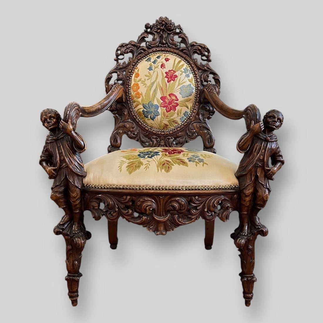 Antique Carved Blackamoor Throne Chair: Antique Carved Blackamoor Throne Chair. Figural arms. Original floral upholstery. There are 2 splits in the wood. Dimensions (in): 45.50" x 33.75" x 22.50"