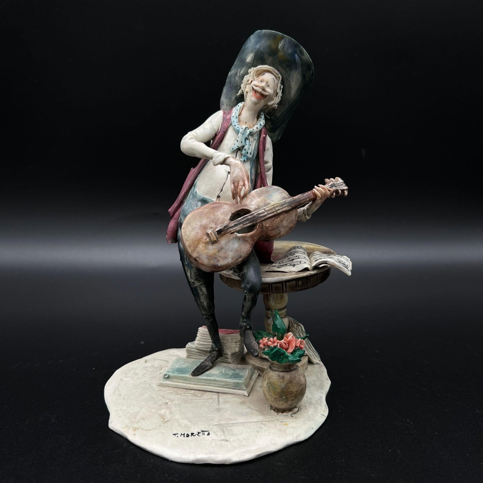 Toni Moretto Guitar Cowboy Ceramic Sculpture: Toni Moretto Guitar Cowboy Ceramic Sculpture. Lo Scricciolo. Depicts a cowboy playing the guitar. Paper label on the bottom. Dimensions (in): 7.25 x 4.75 x 4.75.