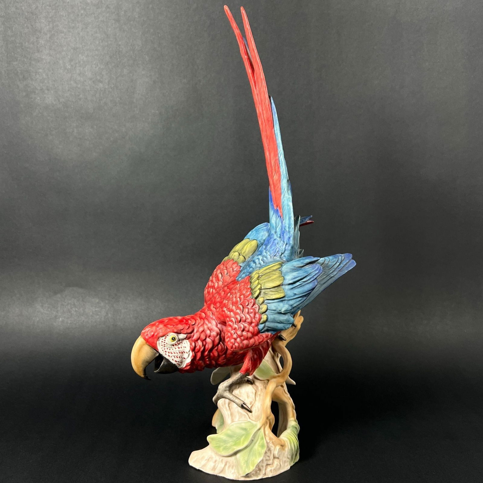 Bochmann Goebel 38517 Red Blue Parrot Figurine: Bochmann Goebel 38517 Red Blue Parrot Figurine. Signed on the interior of the tree. Dimensions (in): 17 x 5.5 x 8.