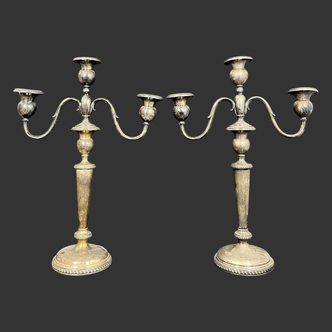 Pair of Sterling Silver Candle Holders Candelabras: Pair of three-light silver candelabras, made of weighted sterling silver, designed to hold three candles each and convertible to single candlesticks. Marked Sterling Silver on the base. 'C24.' Approx.
