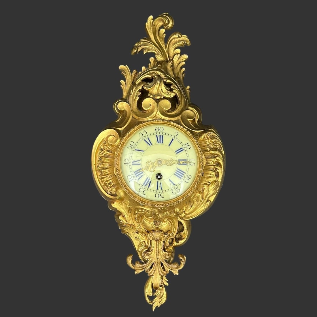 French Rococo Style Cartel Uranium Wall Clock: The face has black Roman numerals for the hours and Arabic numerals for the minutes in increments of five, on a green glowing Uranium Glass surface. Approx. dimensions (in): 20.25 x 9.25 x 4. It is th