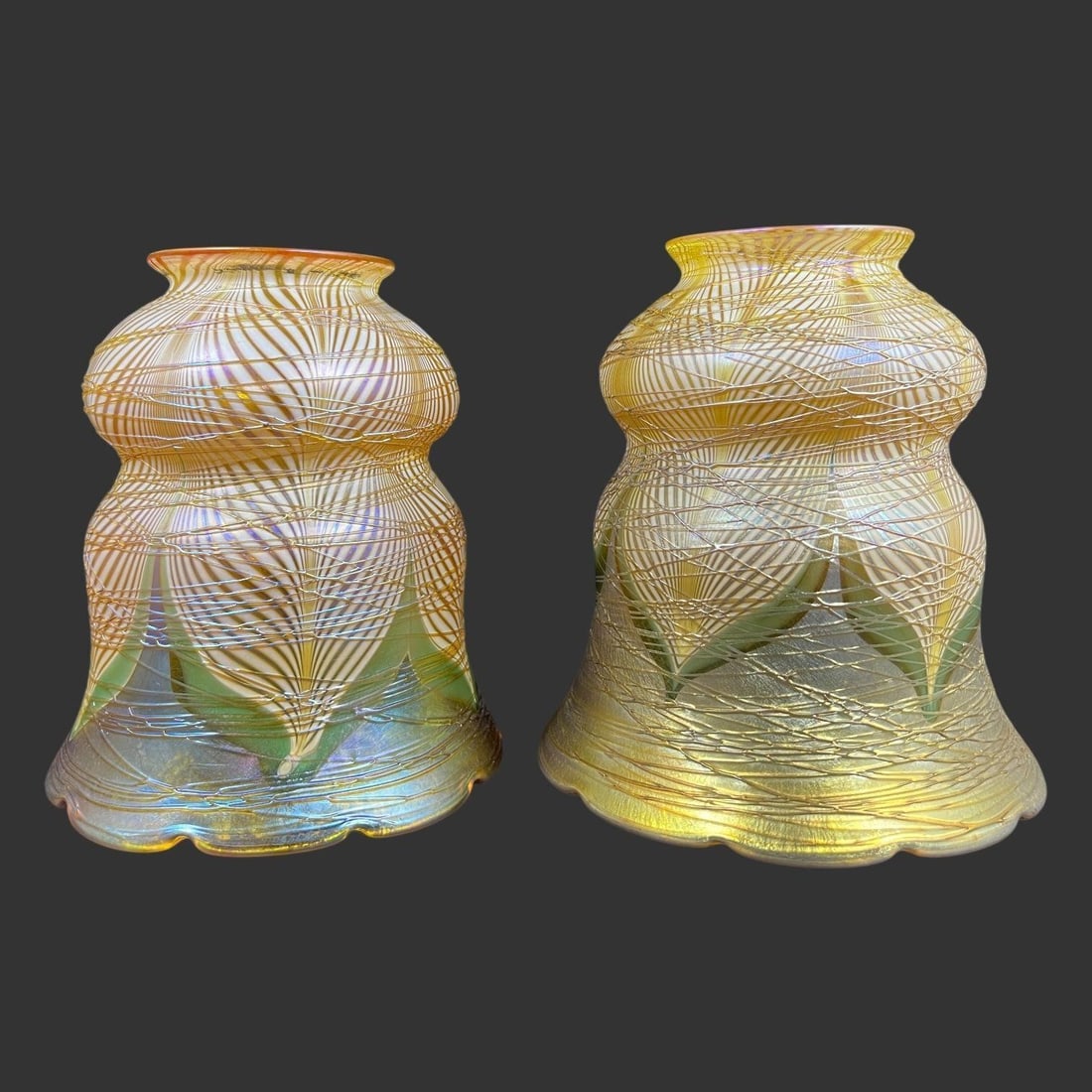 Lot of 2 Pulled Feather Art Glass Lamp Shades: The shades feature a "pulled feather" iridescent design, a common motif in Art Nouveau glass, created by manipulating colored canes of glass while hot. They also have applied threading and a lustrous,
