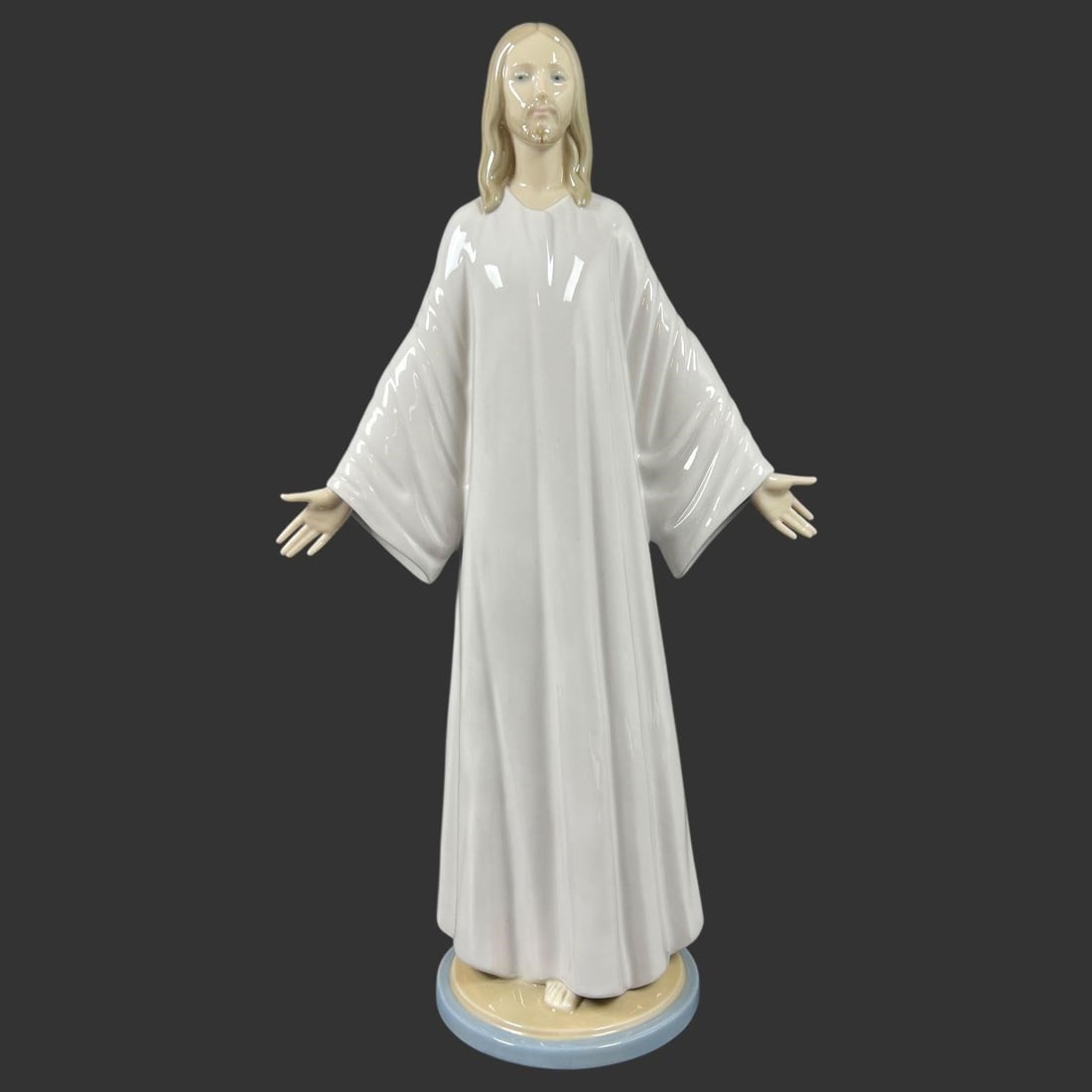 Lladro Spain Porcelain Figure #5167 'Jesus Christ': This elegant Lladro porcelain figure depicts Jesus Christ standing with open arms in a serene and welcoming pose. The figure is rendered in Lladro's signature high-gloss glaze, with a flowing white ro