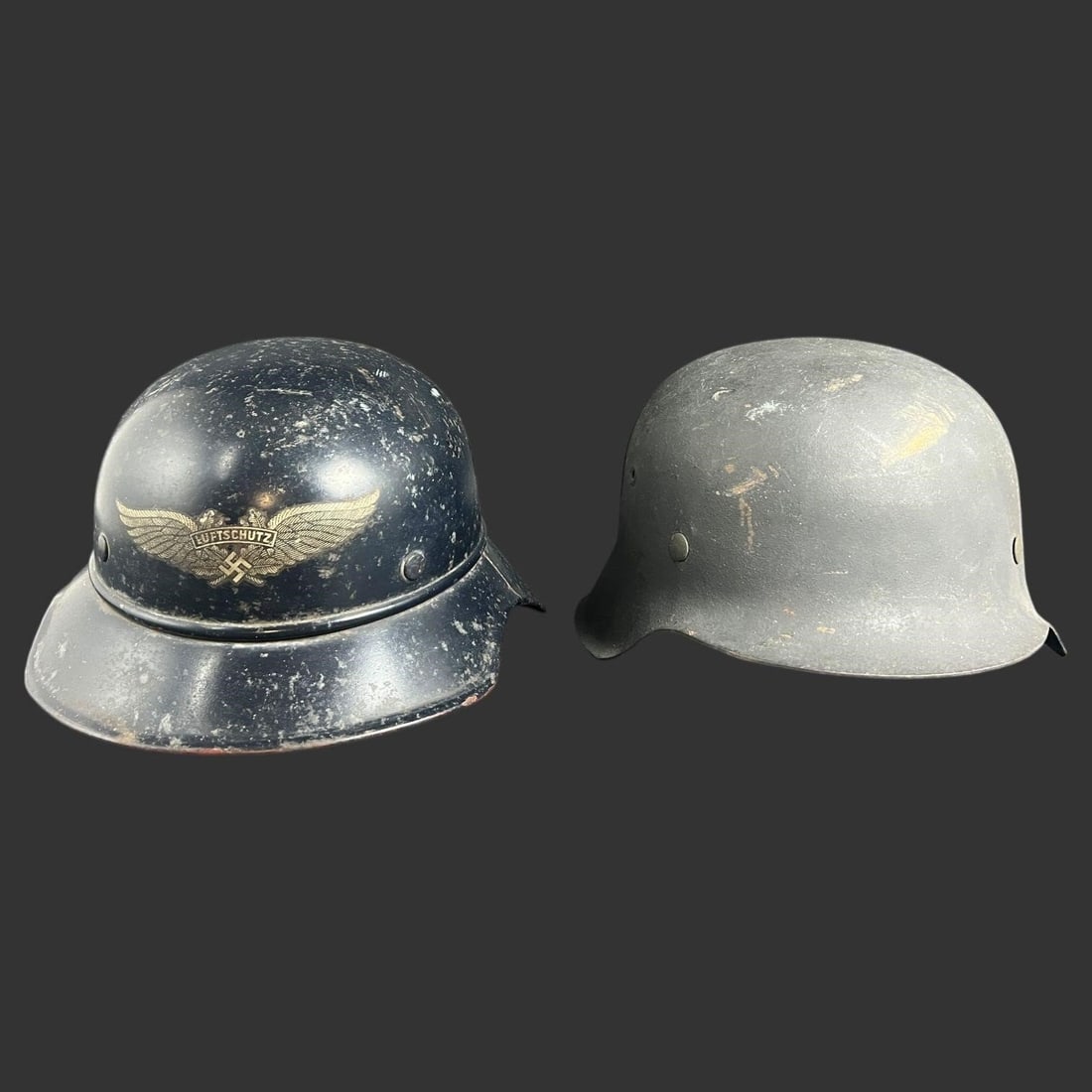 WWII German Luftschutz Helmet Lot (2): This lot consists of two original WWII-era German Luftschutz helmets, each retaining period liners and showing honest service wear throughout. One helmet displays the Luftschutz decal to the front, wi