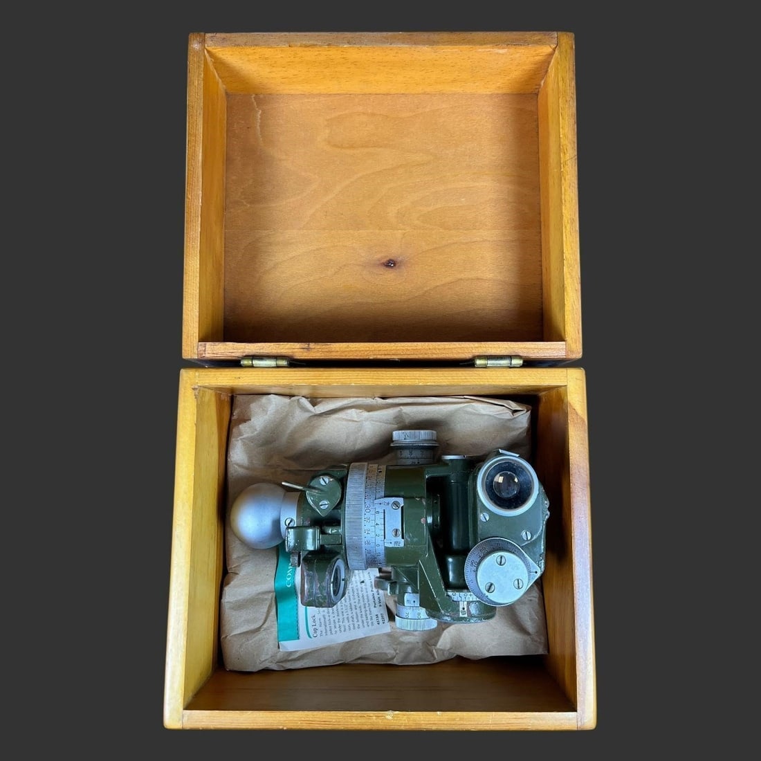 WWII Military Optical Sight in Original Wood Case: Offered here is a World War II-era military optical sight, finished in classic olive drab and housed in its original fitted wooden storage case. The instrument shows all the hallmarks of wartime produ