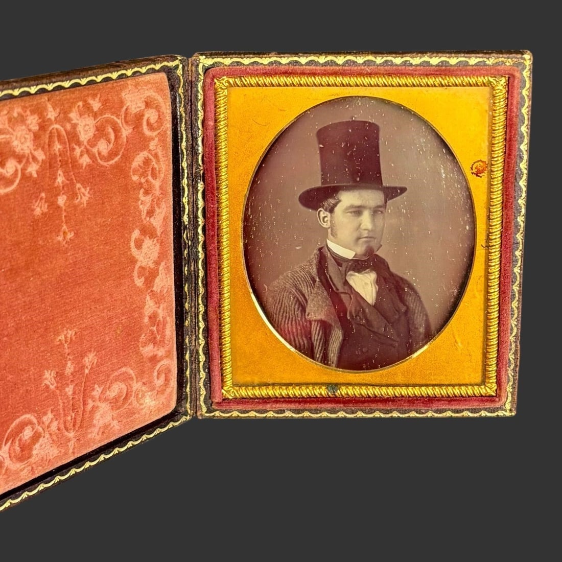 Mid-19th C. Cased Daguerreotype Portrait Photo: Original mid-19th century American daguerreotype portrait depicting a young gentleman wearing a tall top hat, waistcoat, bow tie, and striped coat, presented in its period leather case with deeply emb