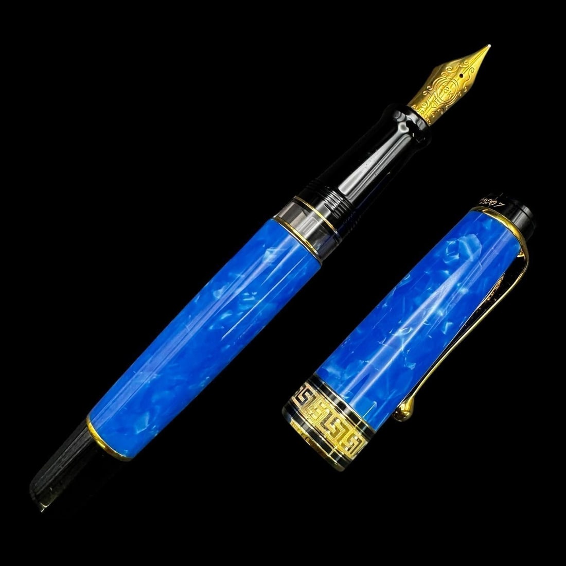 Aurora 18k Blue Marbled Fountain Pen: Elegant Aurora fountain pen featuring a vibrant blue marbled resin barrel and cap accented with gold-tone trim. The pen is fitted with a finely engraved 18K gold nib marked "Aurora," displaying classi