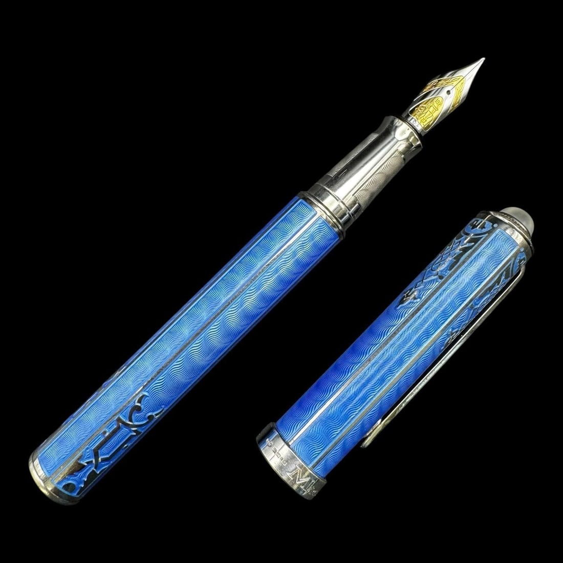 Michel Perchin 18k Blue Guilloche Fountain Pen: Michel Perchin fountain pen featuring a vivid blue guilloche enamel body with ornate silver-tone overlay decoration and a pale cabochon-style finial to the cap. The pen has a hexagonal or faceted form