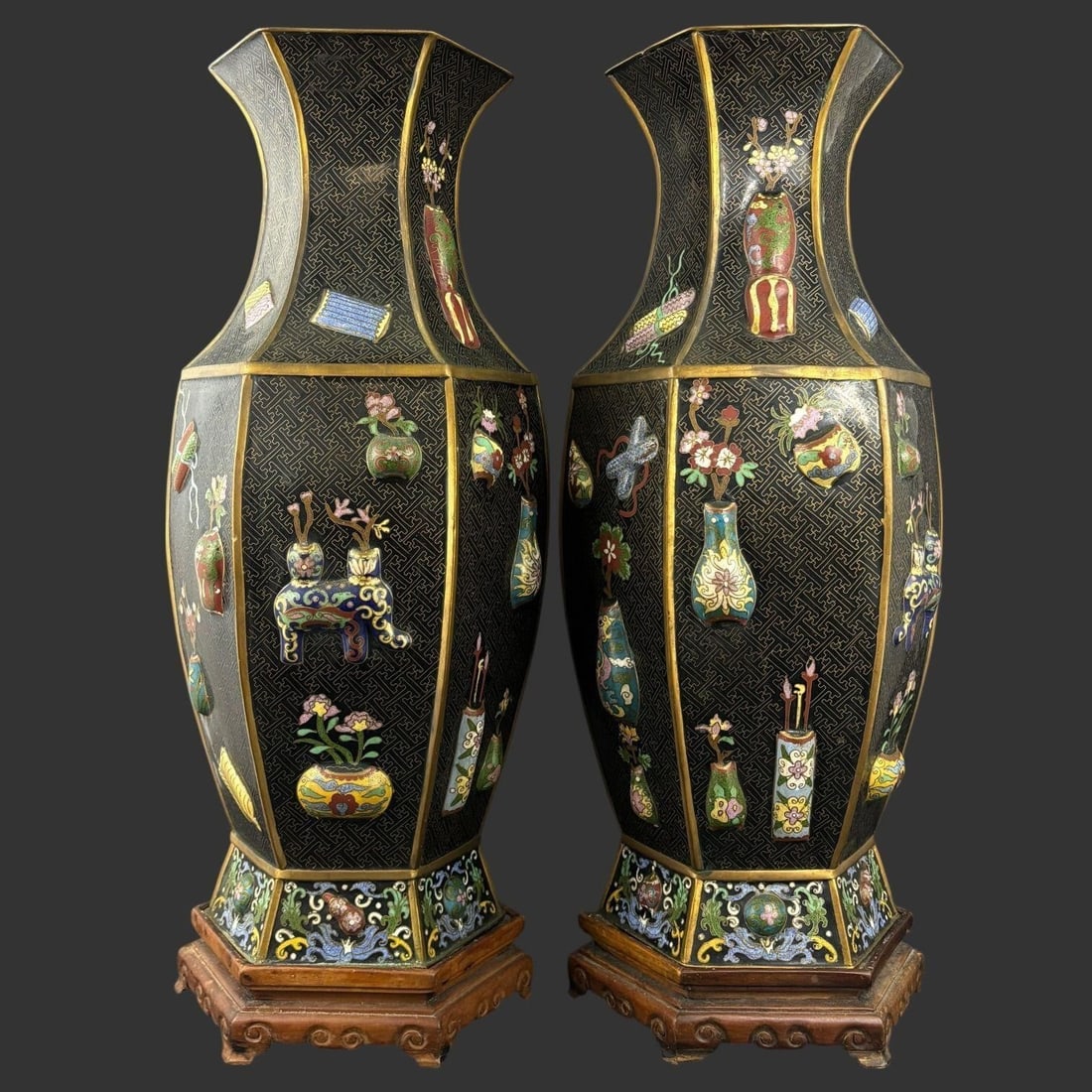 Pair Large Chinese Cloisonne Hexagonal Vases on Stands: Impressive pair of Chinese cloisonnÃ© enamel vases of tall, hexagonal form, each finely decorated on a black ground with intricate geometric diaper patterns and colorful raised panels feat