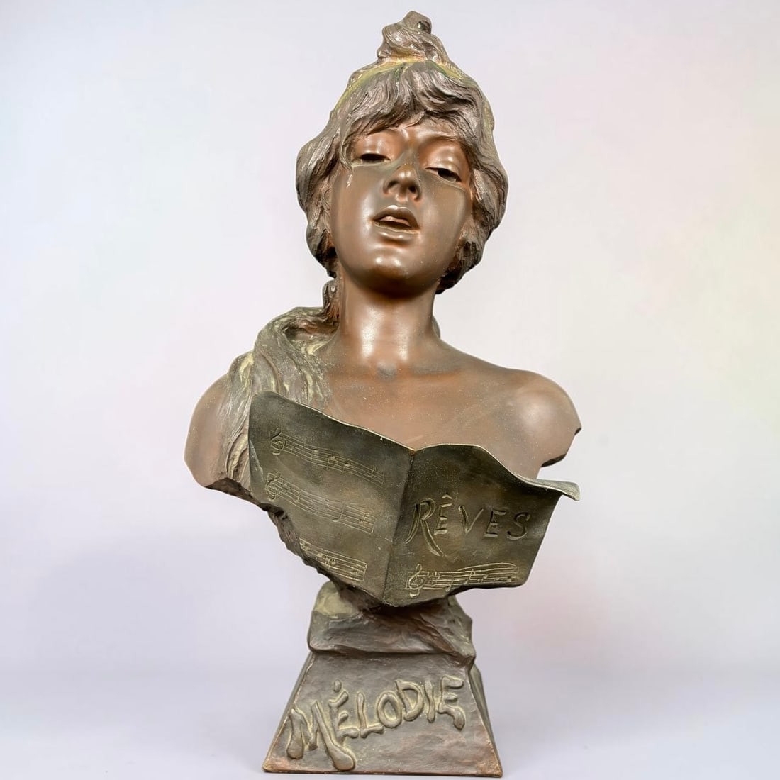 Emmanuel Villanis (French, 1858 - 1914) Art Nouveau Bronze Bust “Mélodie: An elegant Art Nouveau bronze bust titled “Mélodie,” depicting a serene young woman with softly modeled features, upswept hair, and a gilt-highlighted headband, posed above an open 