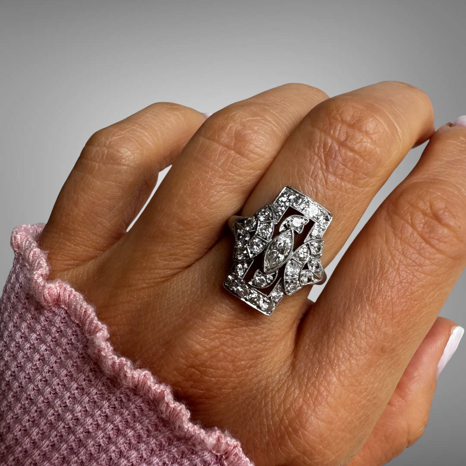 Vintage Art Deco Platinum Diamond Ring: A striking vintage Art Deco ring crafted in platinum, featuring an elegant geometric design with sparkling old-cut and single-cut diamonds. The center marquise-shaped diamond is framed by intricate op