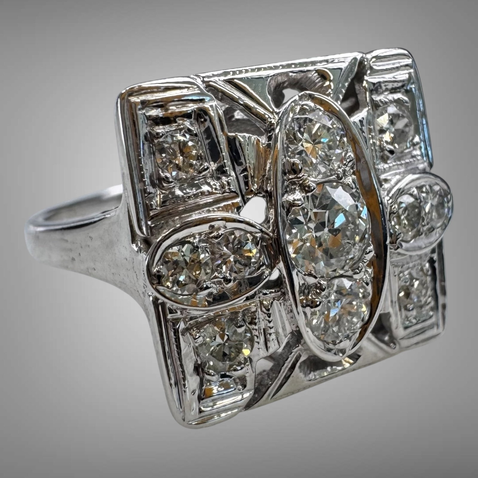 Vintage Art Deco 14K White Gold Diamond Ring: Elegant vintage Art Deco ring crafted in 14K white gold, featuring a striking geometric design set with multiple round-cut diamonds. The centerpiece showcases three larger diamonds in an elongated nav