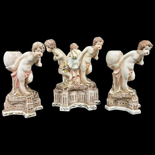 Antique Porcelain Cherub Figural Candleholders / Centerpiece Set: A decorative antique porcelain figural set featuring cherub or putti figures on ornate architectural-style bases, finished in soft cream, blush pink, pale blue, brown, and gilt accents. The lot appear
