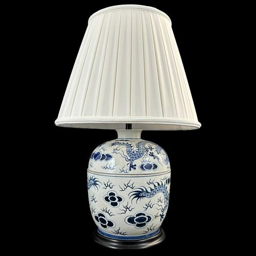 Asian Blue & White Dragon Motif Porcelain Table Lamp: Blue and white porcelain table lamp with rounded jar-form body decorated with dragons, cloud forms, and scrollwork throughout, mounted on a black circular base with brass-tone lamp hardware and harp. 