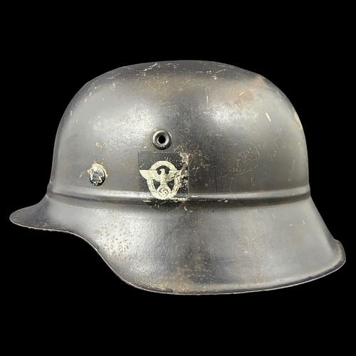 WWII German M34 Civic / Police Helmet with Decals and Leather Liner: Offered here is a WWII-era German M34-style civic or police helmet, retaining its dark painted steel shell, flared brim, side rivets, vent holes, and partial period-style decals, including a shield em