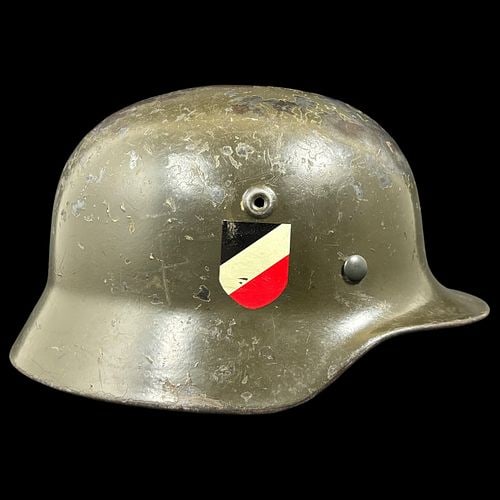 WWII German M35/M40 Double-Decal Steel Combat Helmet with Liner: Original WWII-era German steel combat helmet retaining an olive green painted finish with visible age, surface wear, paint loss, scratches, and oxidation throughout. The helmet features a rolled rim, 