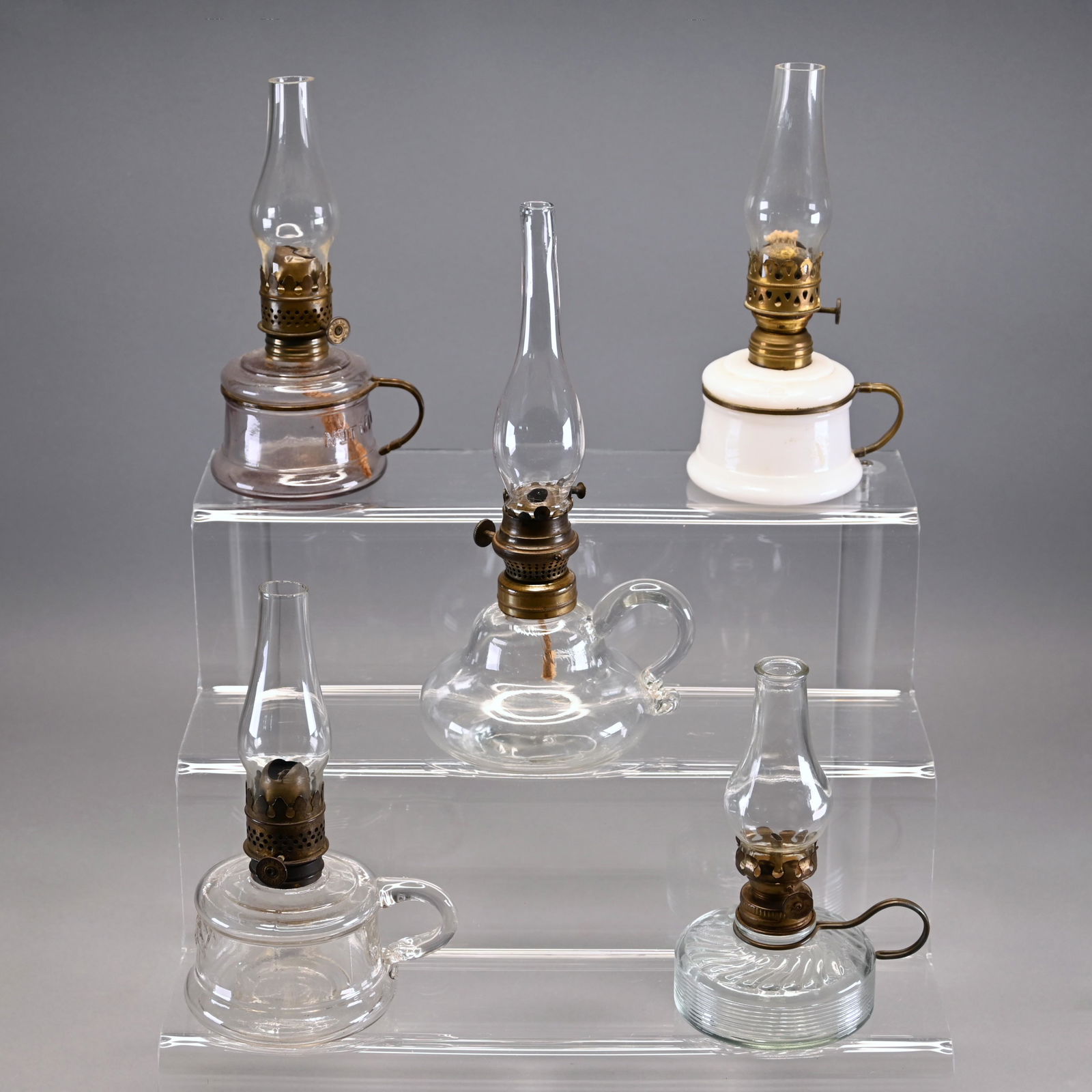 Lot of Five Miniature Glass Finger Lamps: Including an opalescent Nutmeg, a colorless Nutmeg, another colorless with wire handle, a star, crescent moon and elephant embossed colorless and another colorless with applied handle and free blown c