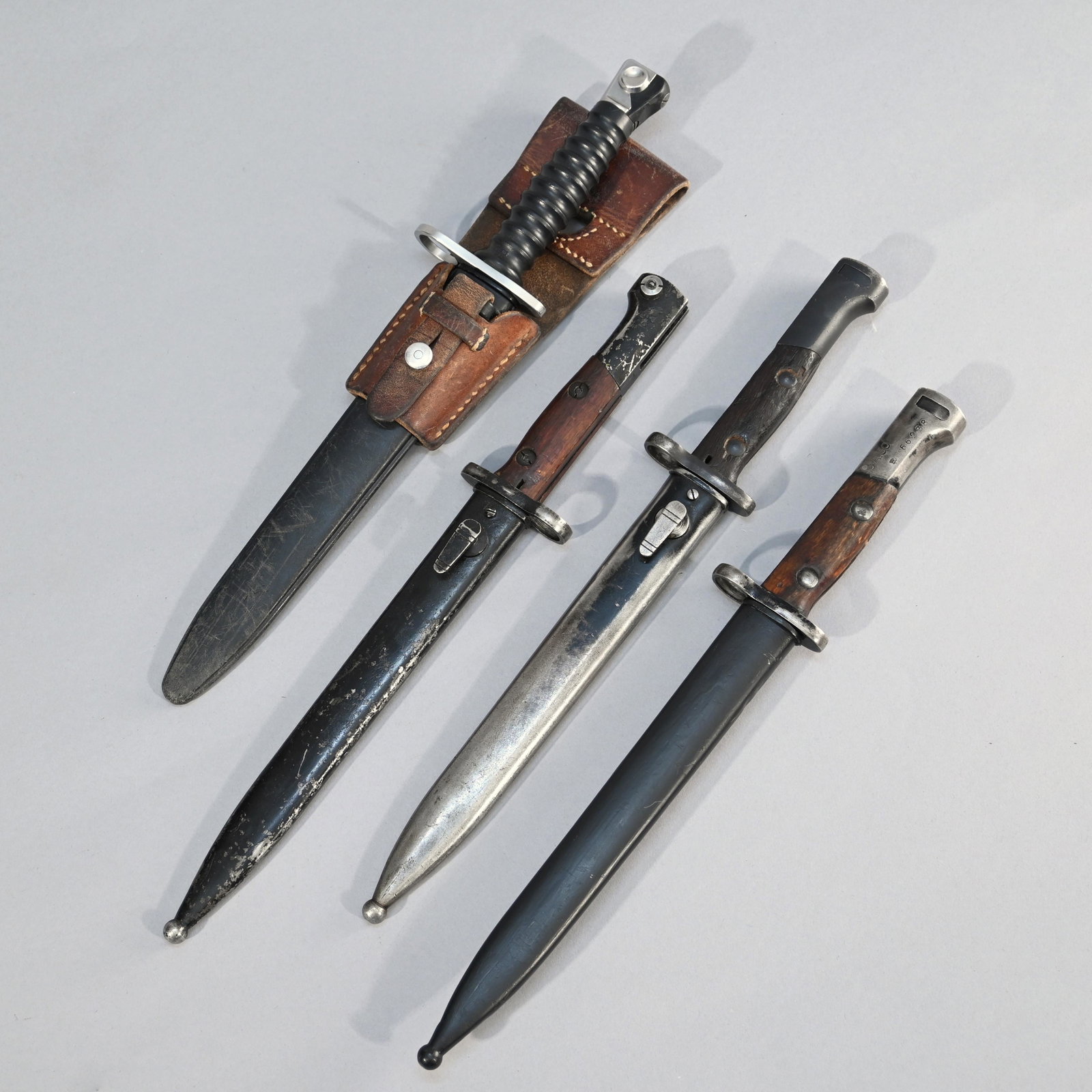 Three Belgian FN-49 Bayonets and a Swiss Mod1957: Each FN-49 bayonet with steel scabbard, blade length: 8.75 inches, 14 inches overall; two marked SA 30 (#3555 & #66238); third unmarked, together with a Swiss Model 1957 bayonet with steel scabbard an