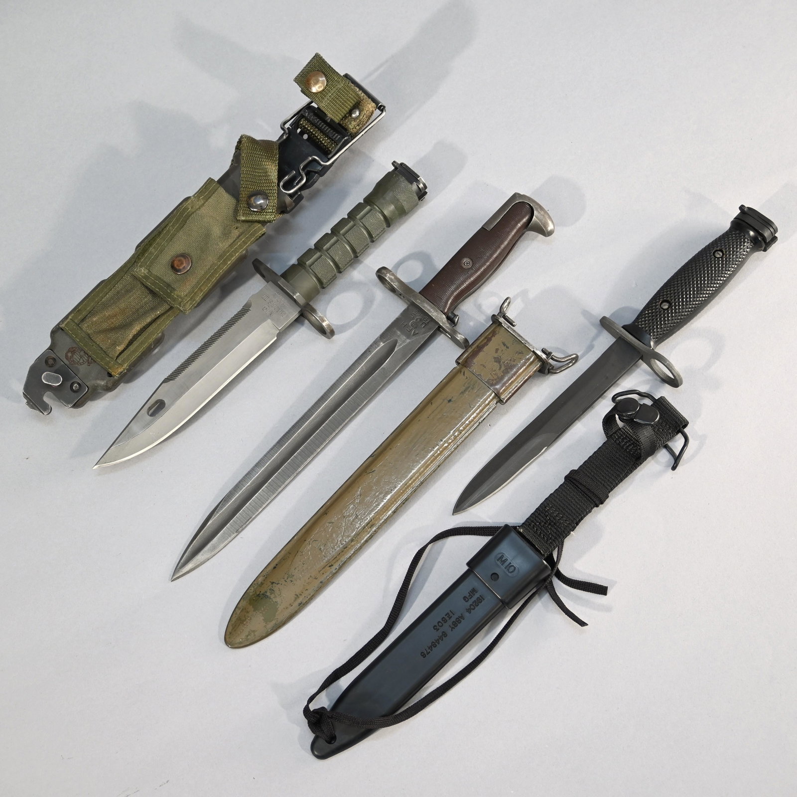 Three US Bayonets and Scabbards: US M1905 Bayonet manufactured by AFH, 1943, cutdown and fitted with M7 scabbard, blade length: 10 inches; 14.5 inches overall, together with an M7 bayonet with M10 scabbard, blade length: 6.625 inches
