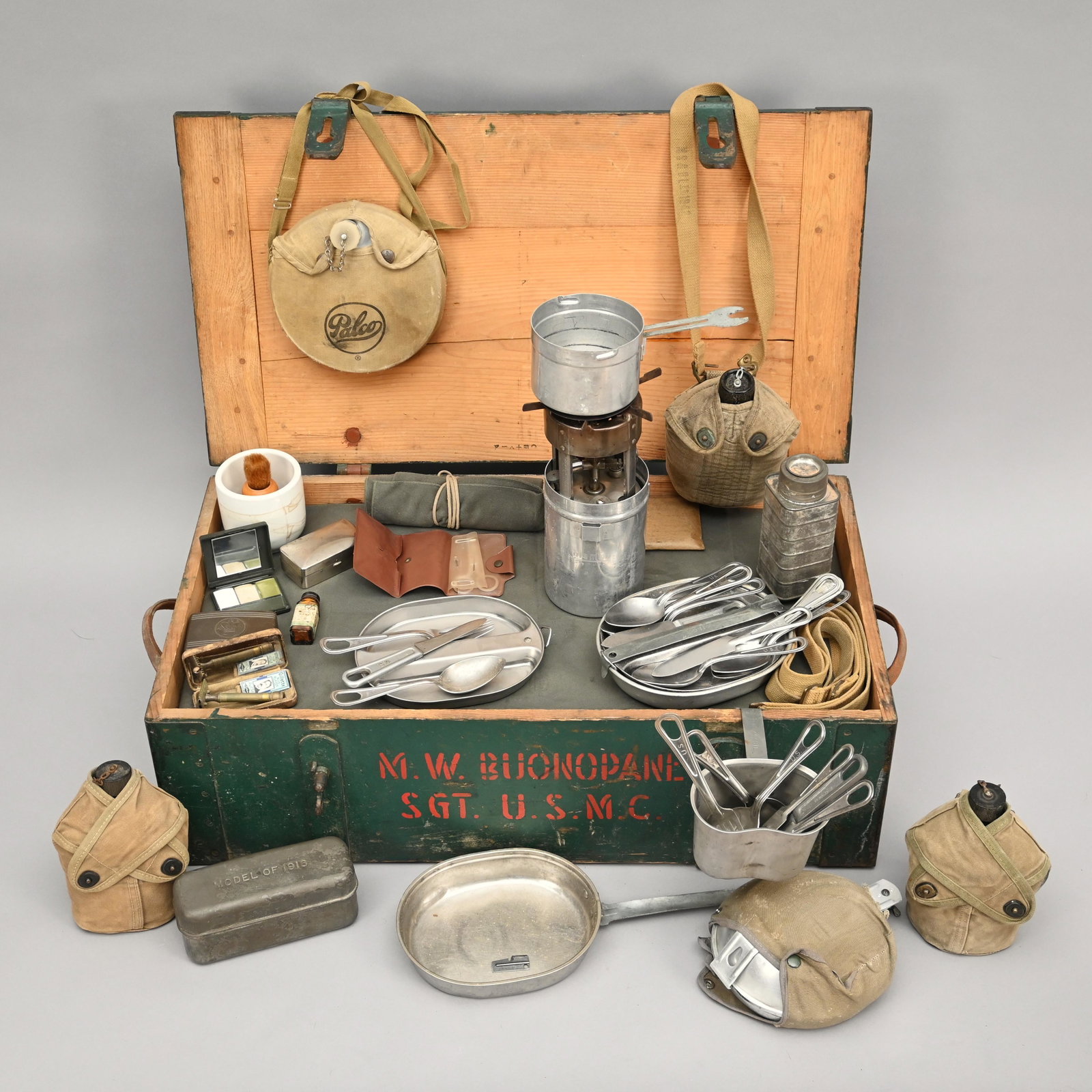 Lot of US Military Mess Accessories & Footlocker: Wooden foot locker, "M. W. Buonopane, S.G.T. USMC", with a Coleman GI pocket stove & box, (3) military canteens, (2) US mess kits & utensils, a "model of 1916" mess tin, shaving kit, toiletries, etc.