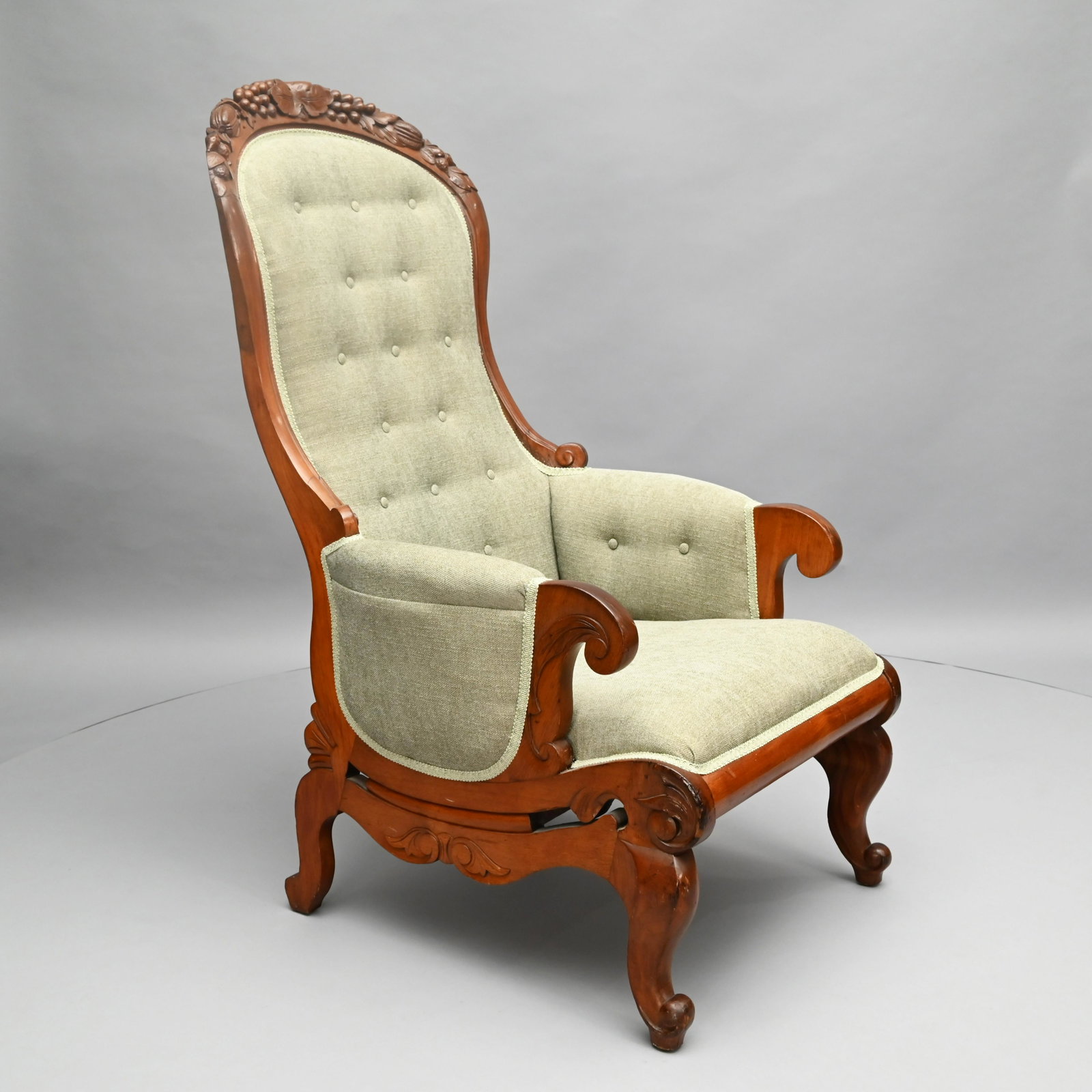 American Renaissance Revival Walnut Armchair: The fruit-carved crest rail above an upholstered back, seat and arms, over scrolled handholds, above a scroll and acanthus-carved frame, raised on squat cabriole legs ending in scrolled feet and pads.