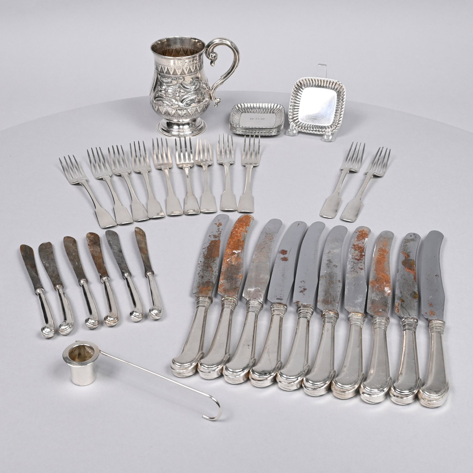 Group of British Silver Flatware and A Mug: Various Makers, Nineteenth Century. Comprising a set of 9 George III 'Tipped Fiddle' pattern forks, Thomas Wilkes Barker, London, 1816, each engraved on the reverse with a badge and motto "NEC PARVIS 