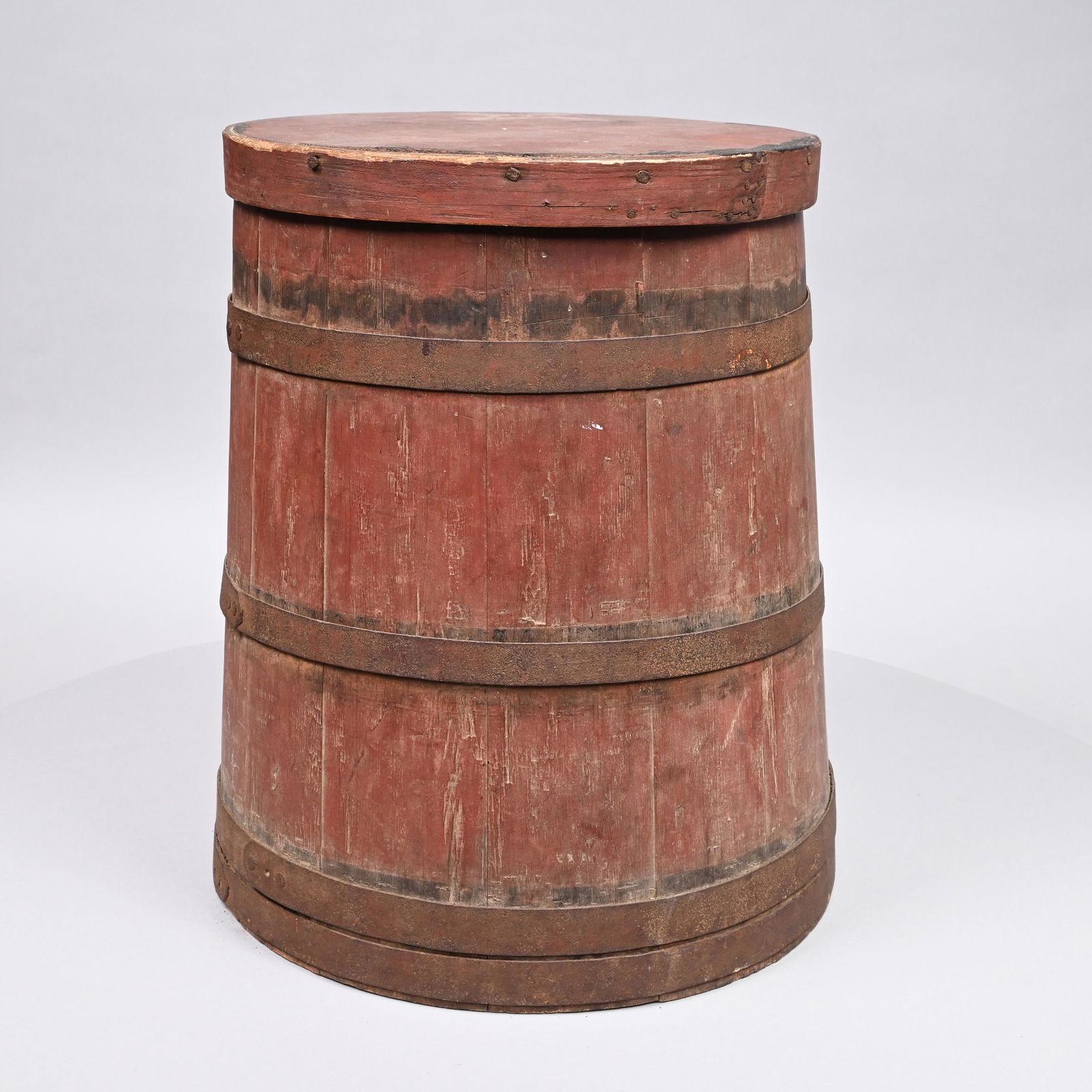 19th Century Pine Lidded Bucket in Red Paint: The circular lid above a conforming flared iron-bound staved container. H: 18 in.; Diam.: 15 in. (base)