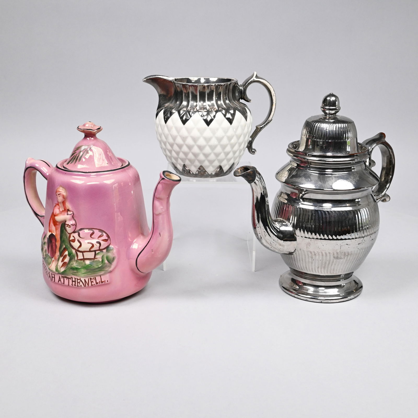 Three Staffordshire Lustre-Decorated Wares, 19th C: Comprising a pearlware white-ground and silver-lustre 'Pineapple' jug, 1815-25; an enamel-decorated pink-ground 'Rebekah-at-the-Well' teapot, circa 1860; and a redware silver lustre coffeepot and cove