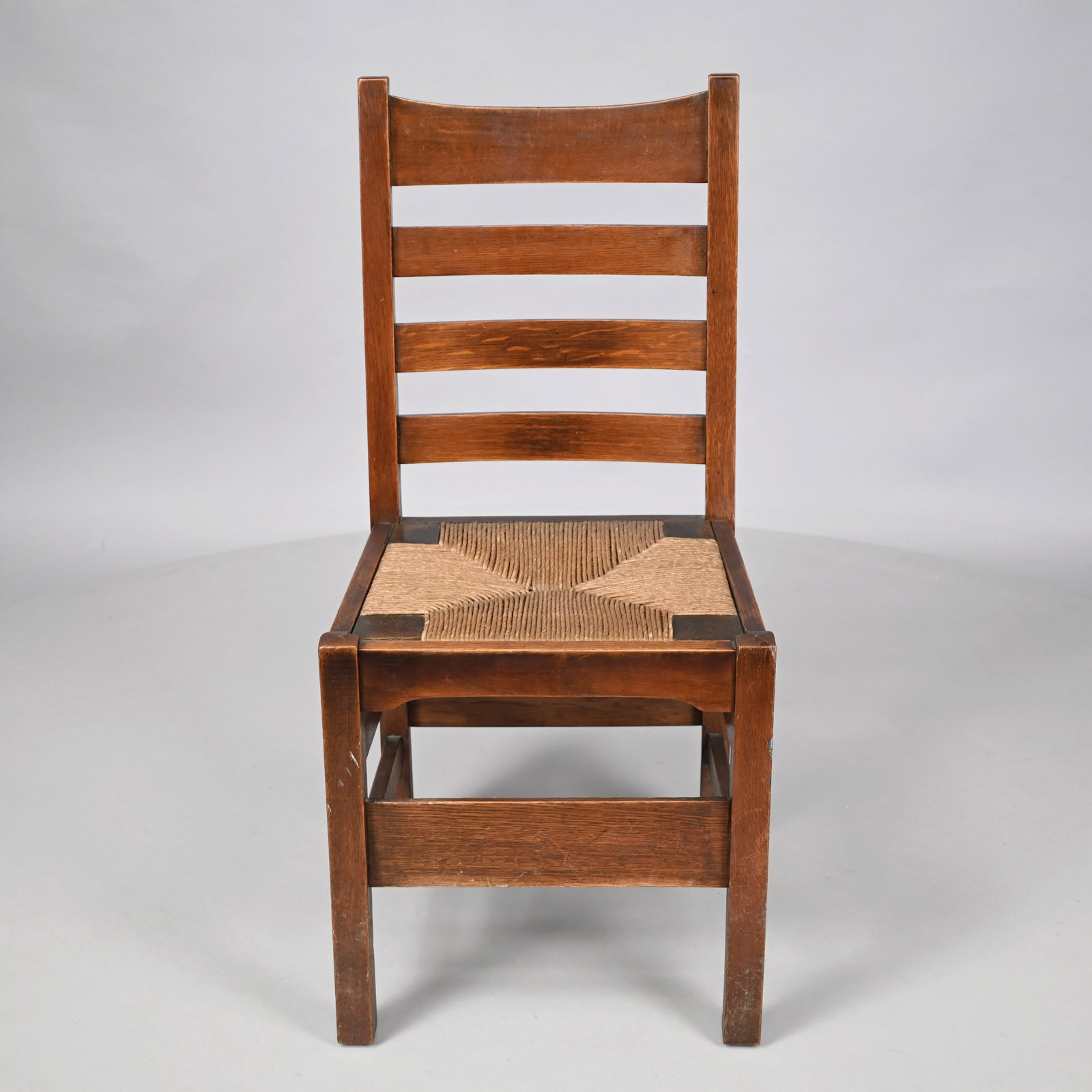 Arts & Crafts Oak #1297 Chair,Gustav Stickley Co.: Syracuse, New York, 1912-16. The curved crest rail above three splats over a rush seat, raised on square legs joined by wide front and back stretchers and two side stretchers. H: 37.5 in., W: 18 in., 