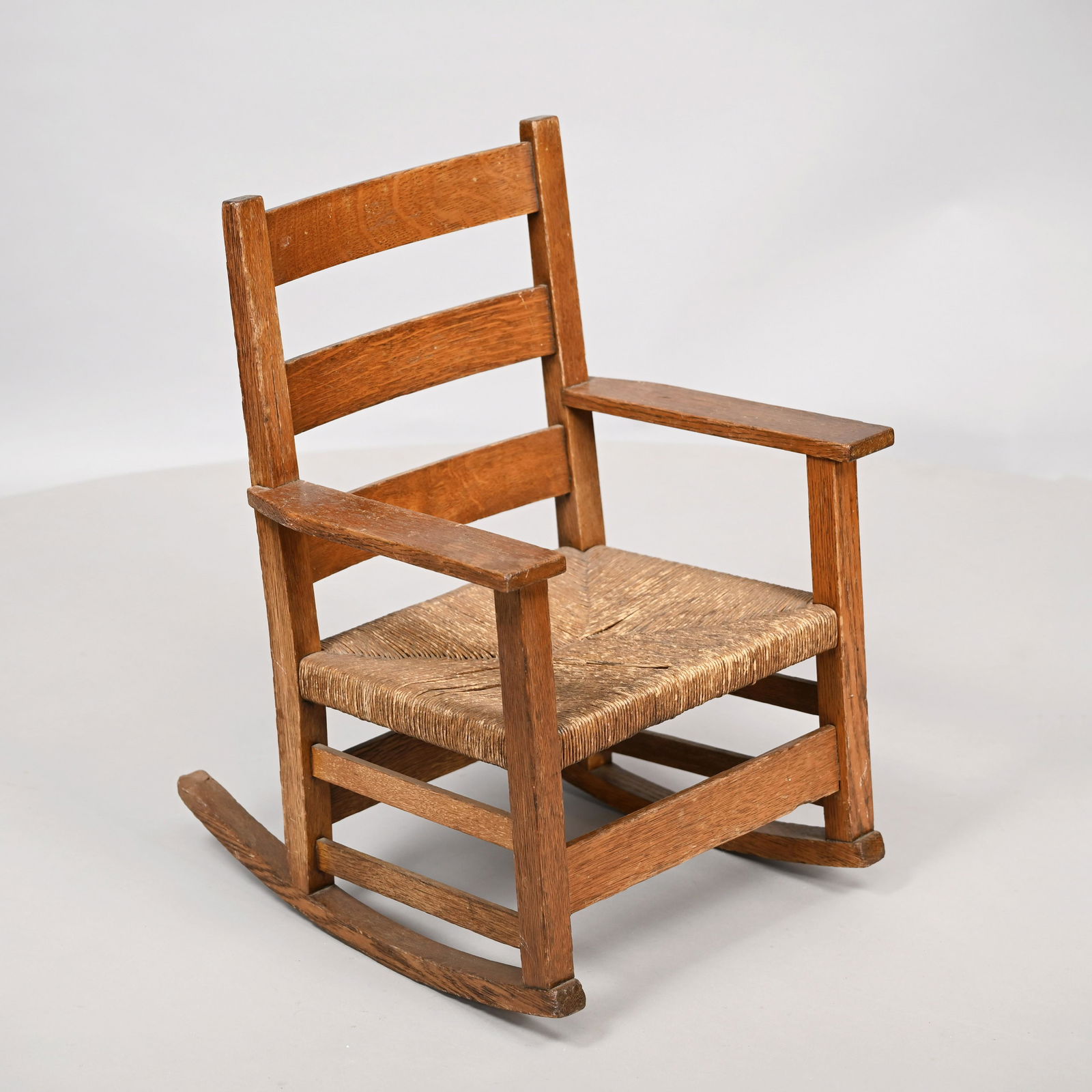 Arts & Crafts Oak #345 Rocking Chair, G.Stickley: Arts & Crafts Oak Child's #345 Rocking Chair, Gustav Stickley Co., Syracuse, New York, 1904-07. The three splats and rectangular arms above a rush seat, raised on square legs joined by wide front and