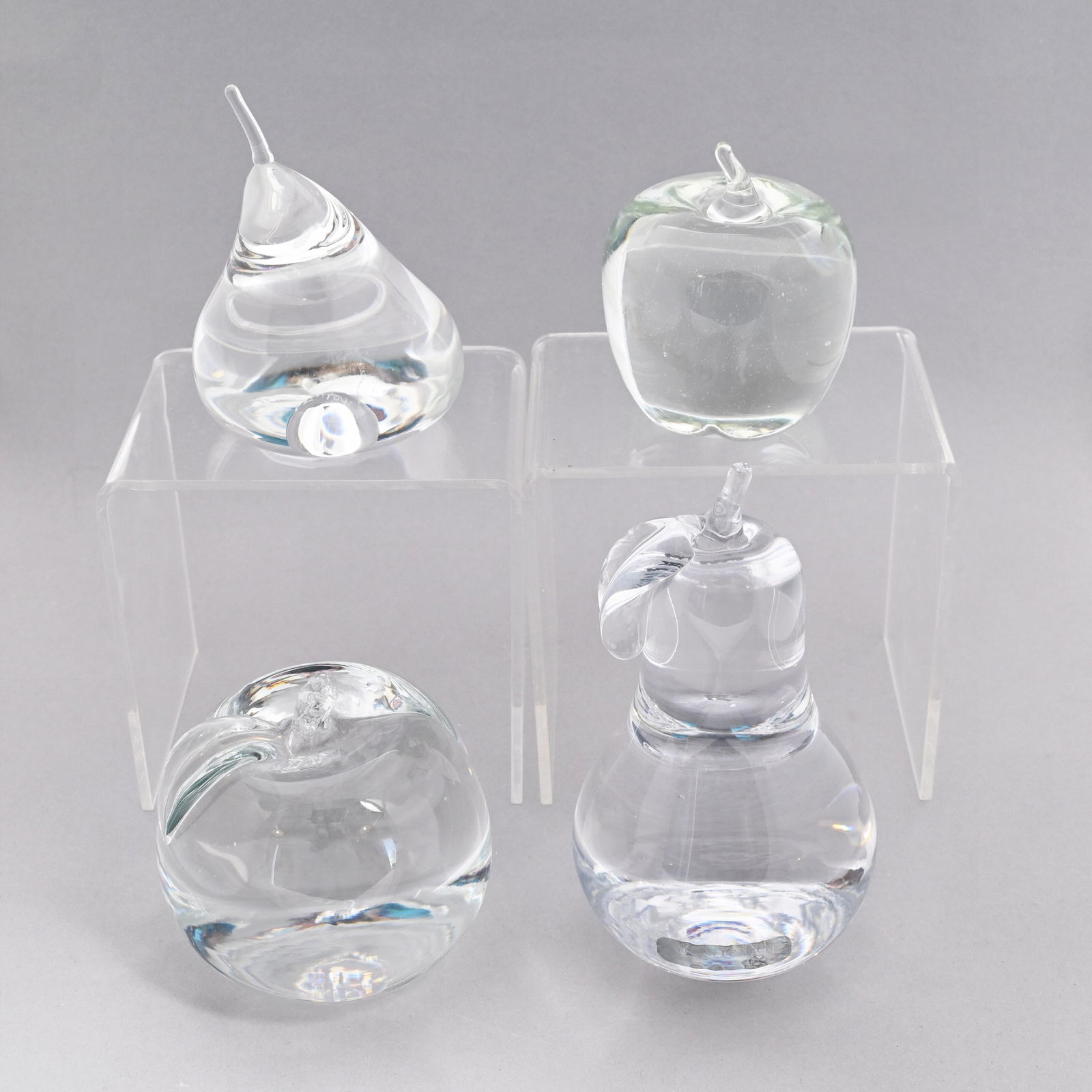 Four American Glass Hand Coolers/ Paperweights: Comprising an apple and a pear, Simon Pearce, Quechee, Vermont, each etched "Simon Pearce," the pear also affixed with a label; a fig, Steuben Glass Works, Corning, New York, etched "Steuben;" and an