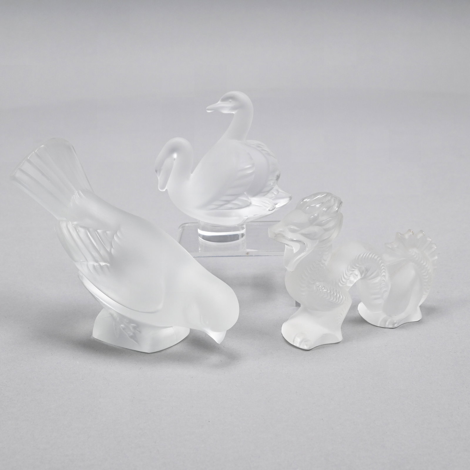 Three French Frosted Glass Hand Coolers/ Weights: After 1945. Comprising a pecking sparrow, a pair of conjoined swans and a dragon, each etched "Lalique France." Sparrow: H: 3.875 in., W: 5 in., D: 2.125 in.