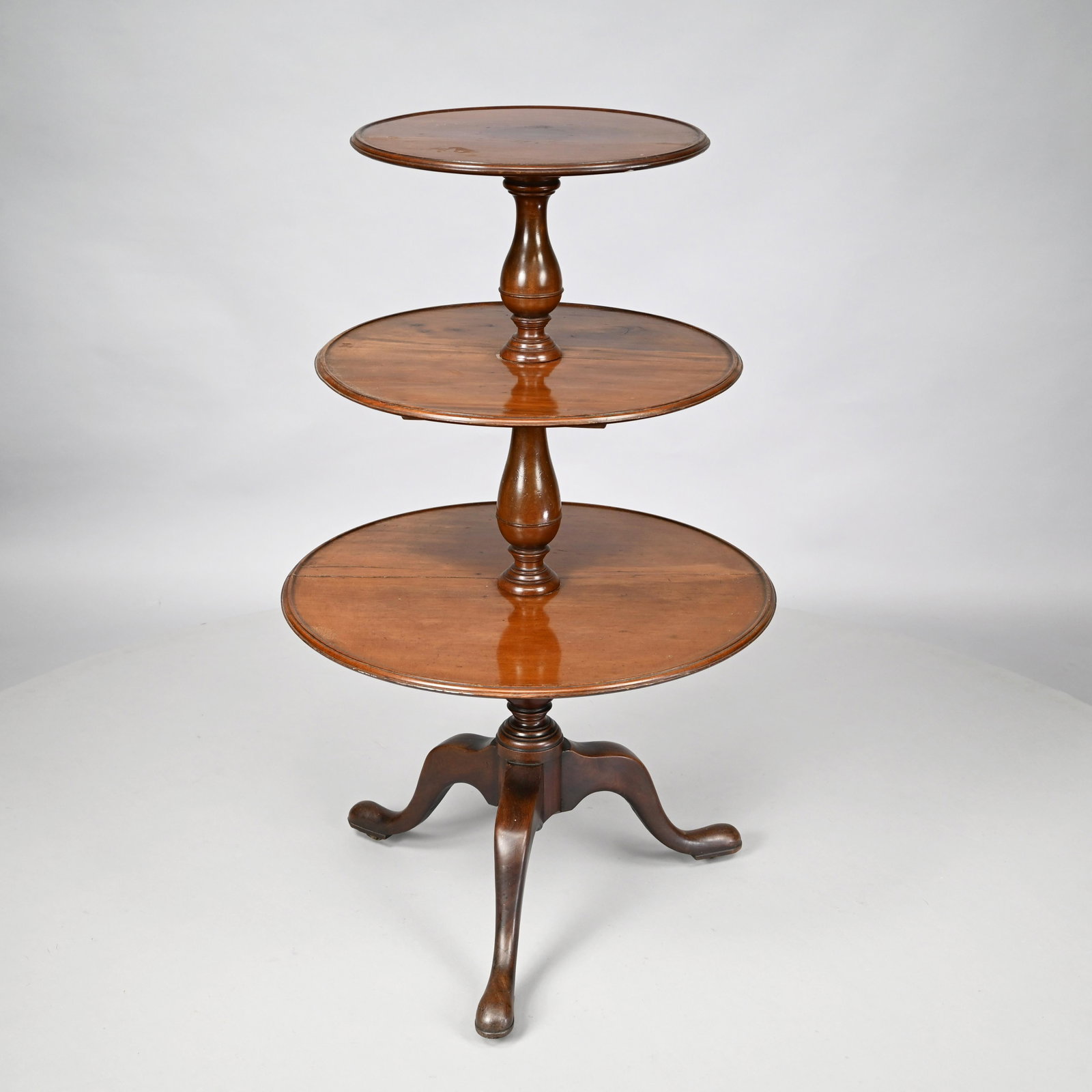 Regency Mahogany Three-Tier Dumbwaiter: Each tier within a molded edge and on a turned baluster support, raised on cabriole legs ending in snake feet. H: 44.5 in., W: 27 in., D: 27 in.