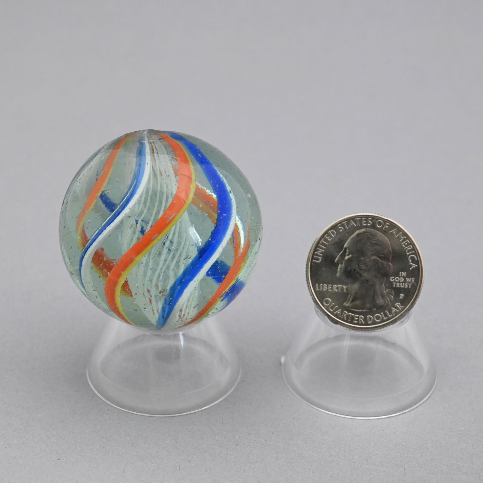 Large Latticinio Marble: Composed of cobalt blue, orange, yellow and white swirls with a white latticinio core. Diameter: 1 9/16 in.