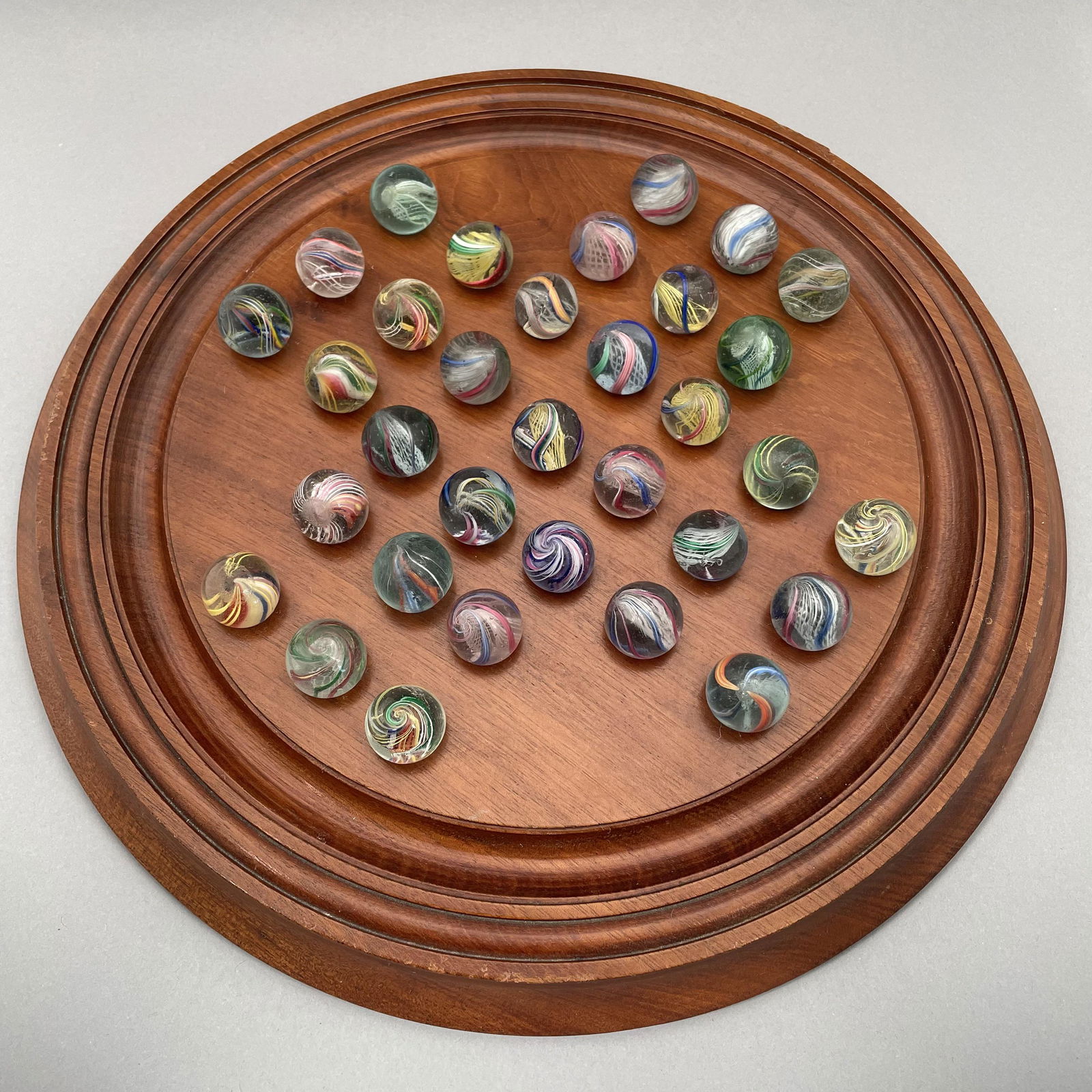 Solitaire Board with Thirty-Three Marbles: The marbles handmade and comprising swirls. Approximate range of diam: 89/128 to 101/128 inch Board: Diam: 11.375 in., D: 1 in.