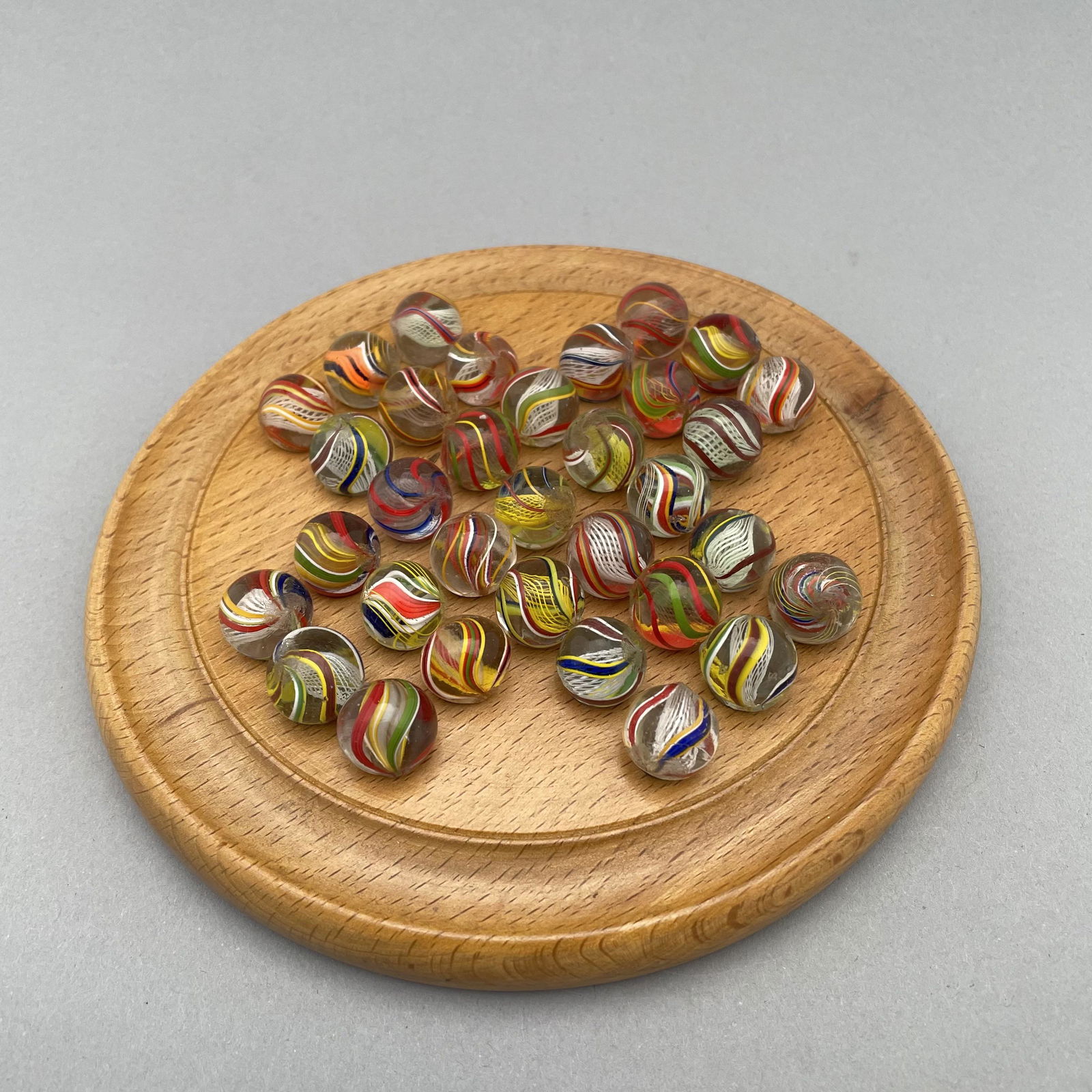 English Solitaire Board with Thirty-Three Marbles: The marbles handmade and comprising swirls; housed in the original box marked "SOLITAIRE INTERNATIONAL SERIES" and "MADE IN ENGLAND." Approximate range of diam: 35/64 to 77/128 in. Board: 6.125 in., D
