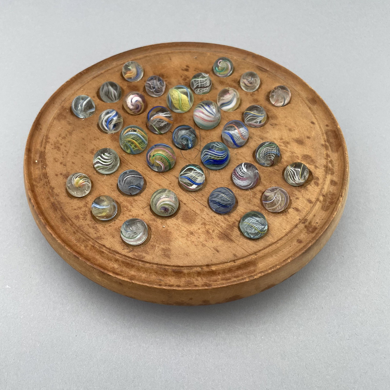 General Grant Board, Thirty-Three Pee Wee Marbles: The marbles handmade and comprising swirls. Approximate range of diam: 29/64 to 75/128 in. Board: 6.375 in., D: 1.375 in.
